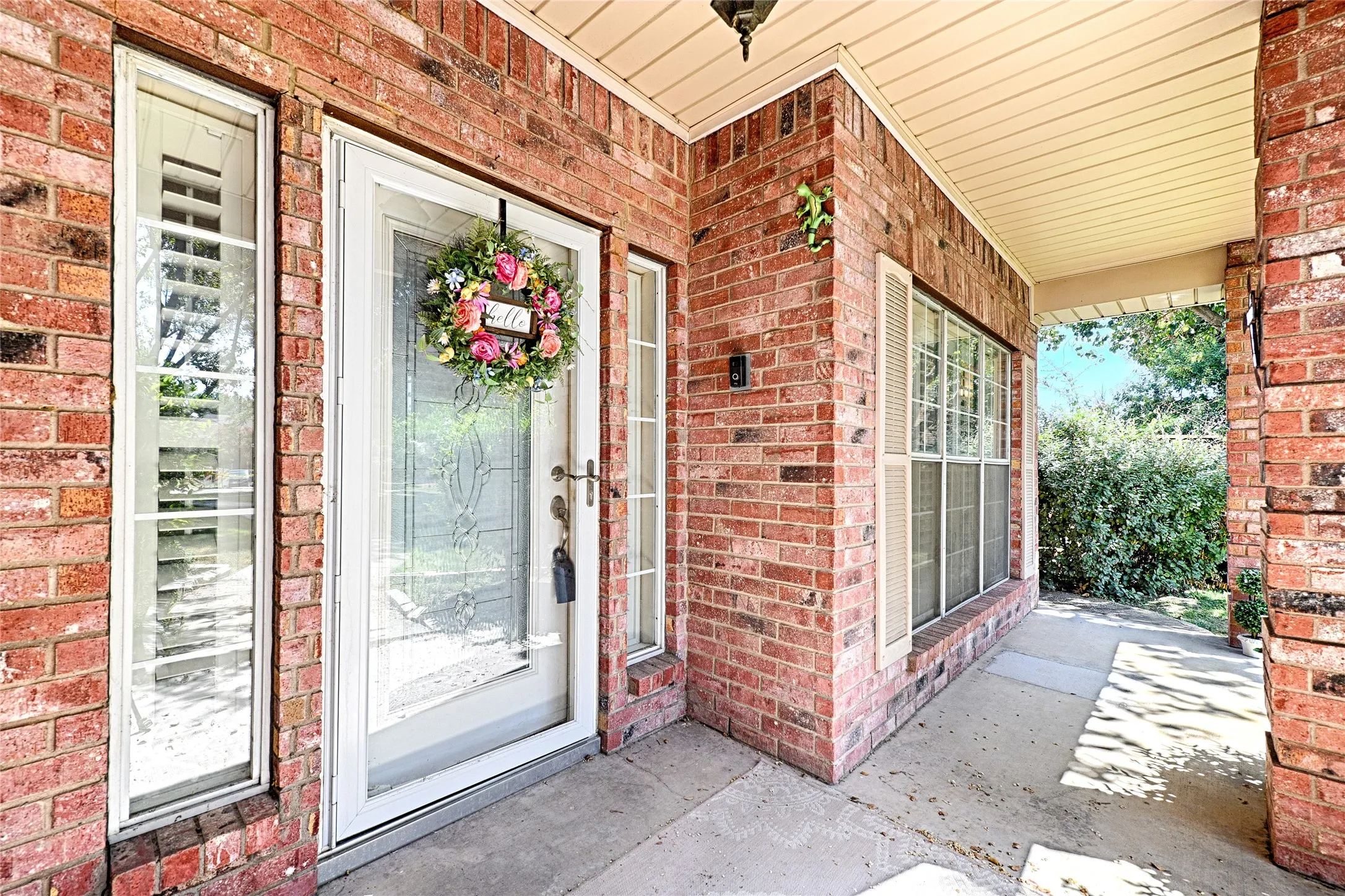 Brick exterior with a covered porch, decorative glass entry door, and side-panel windows