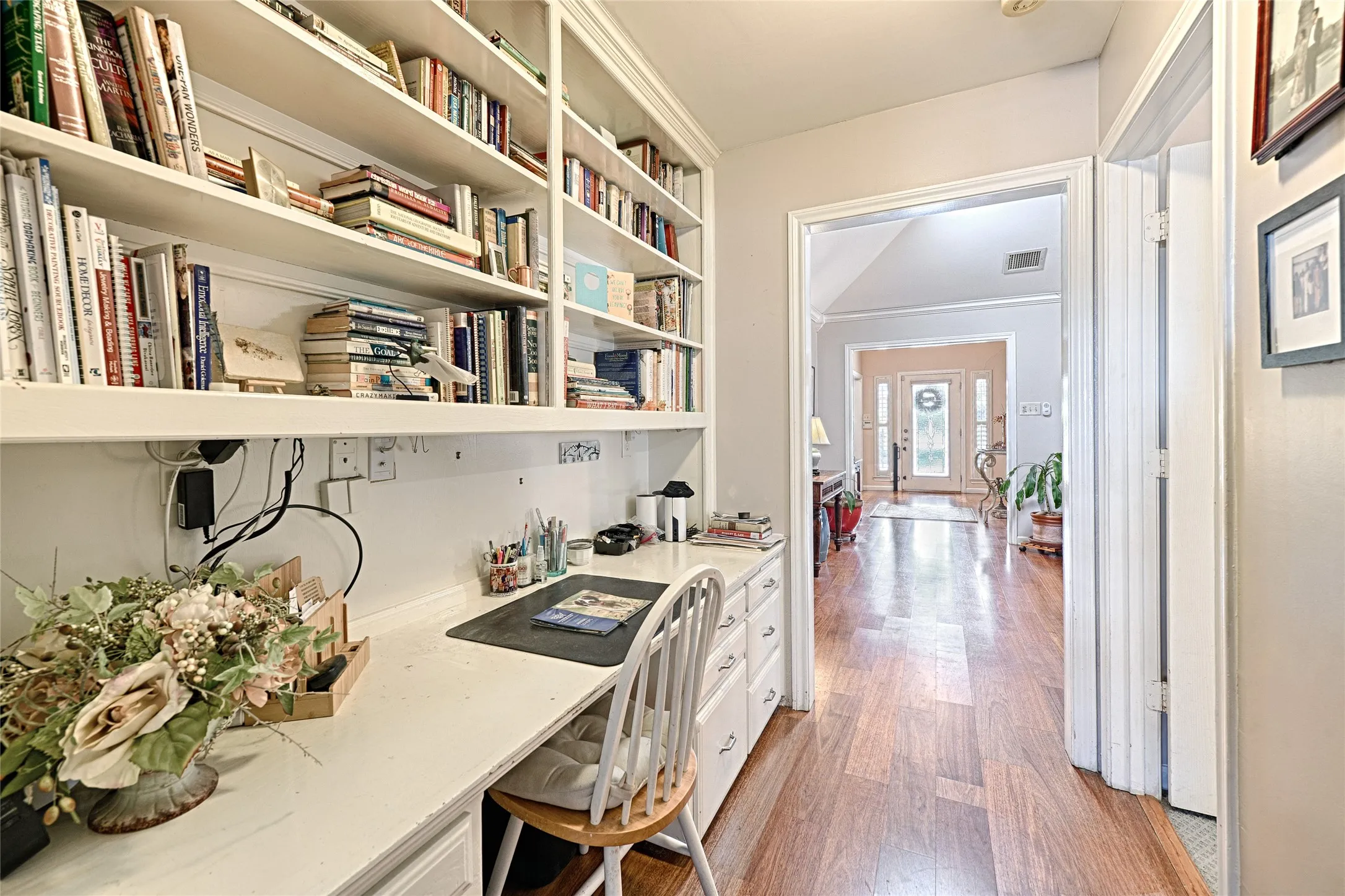 Built-in desk with integrated shelving, white cabinetry, and wood-finish flooring