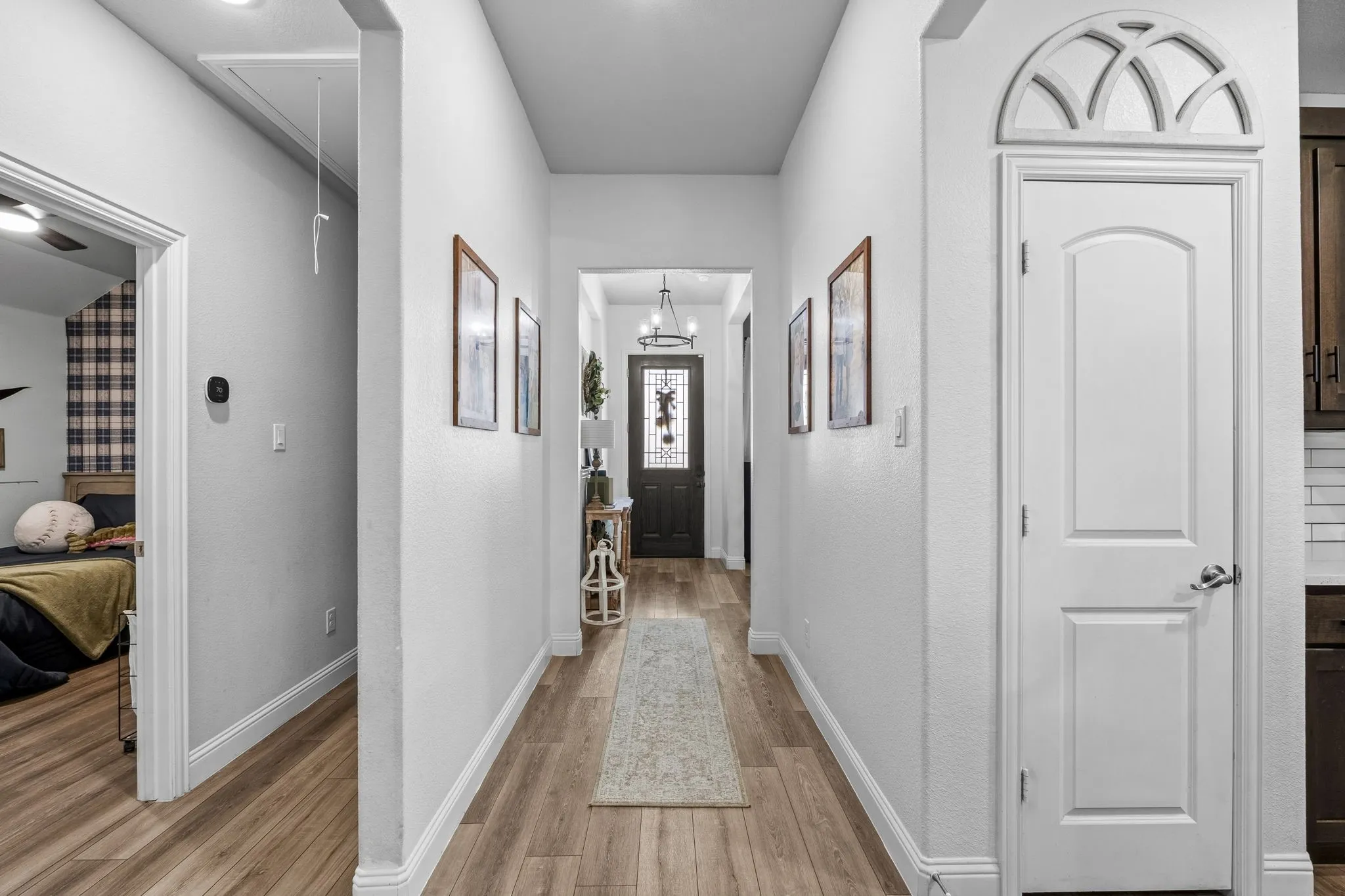 Hallway with wood-finish flooring, recessed lighting, and a decorative archway above a paneled door