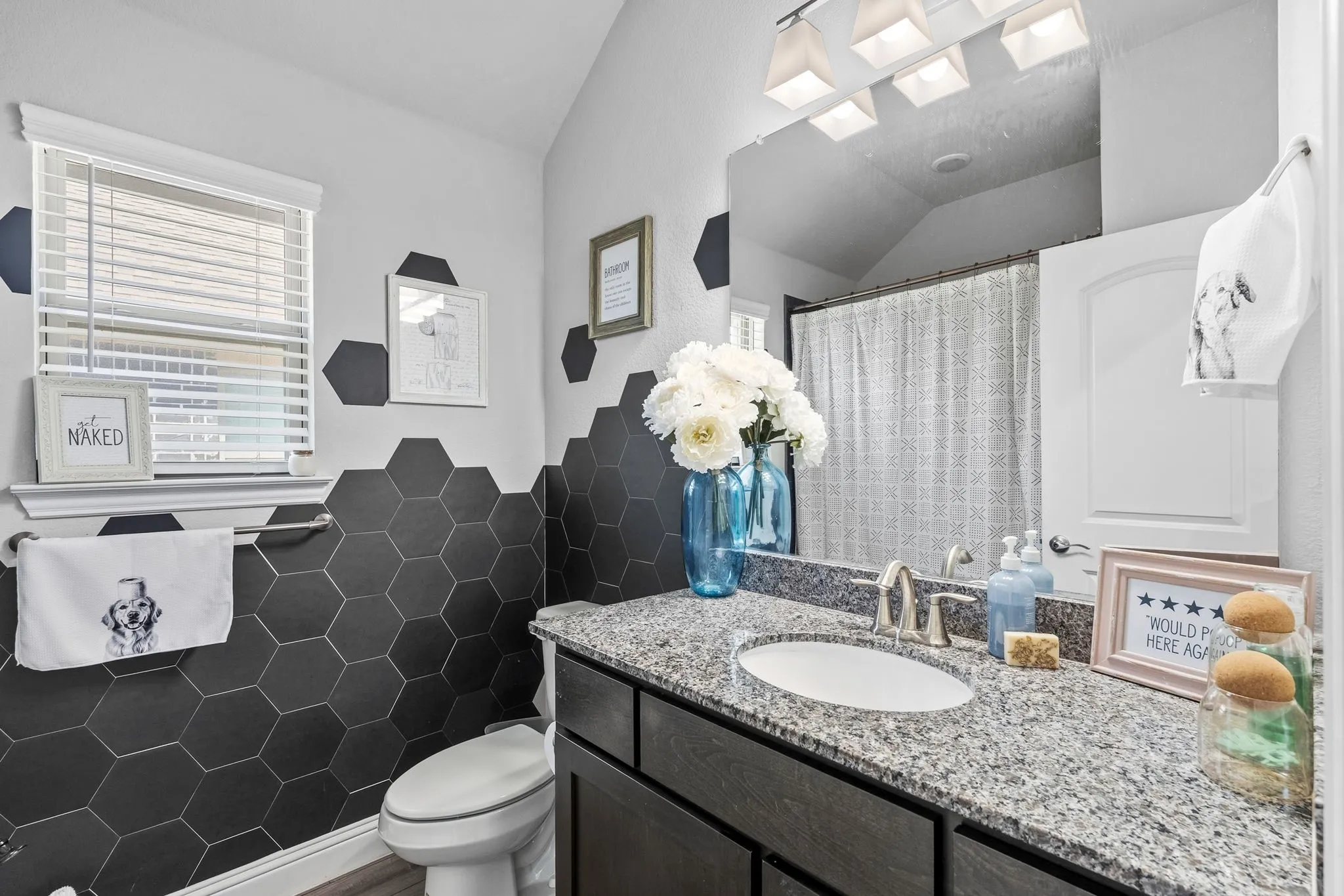 Hexagonal wall tile detailing, single vanity with granite-style countertop, undermount sink, and brushed nickel faucet