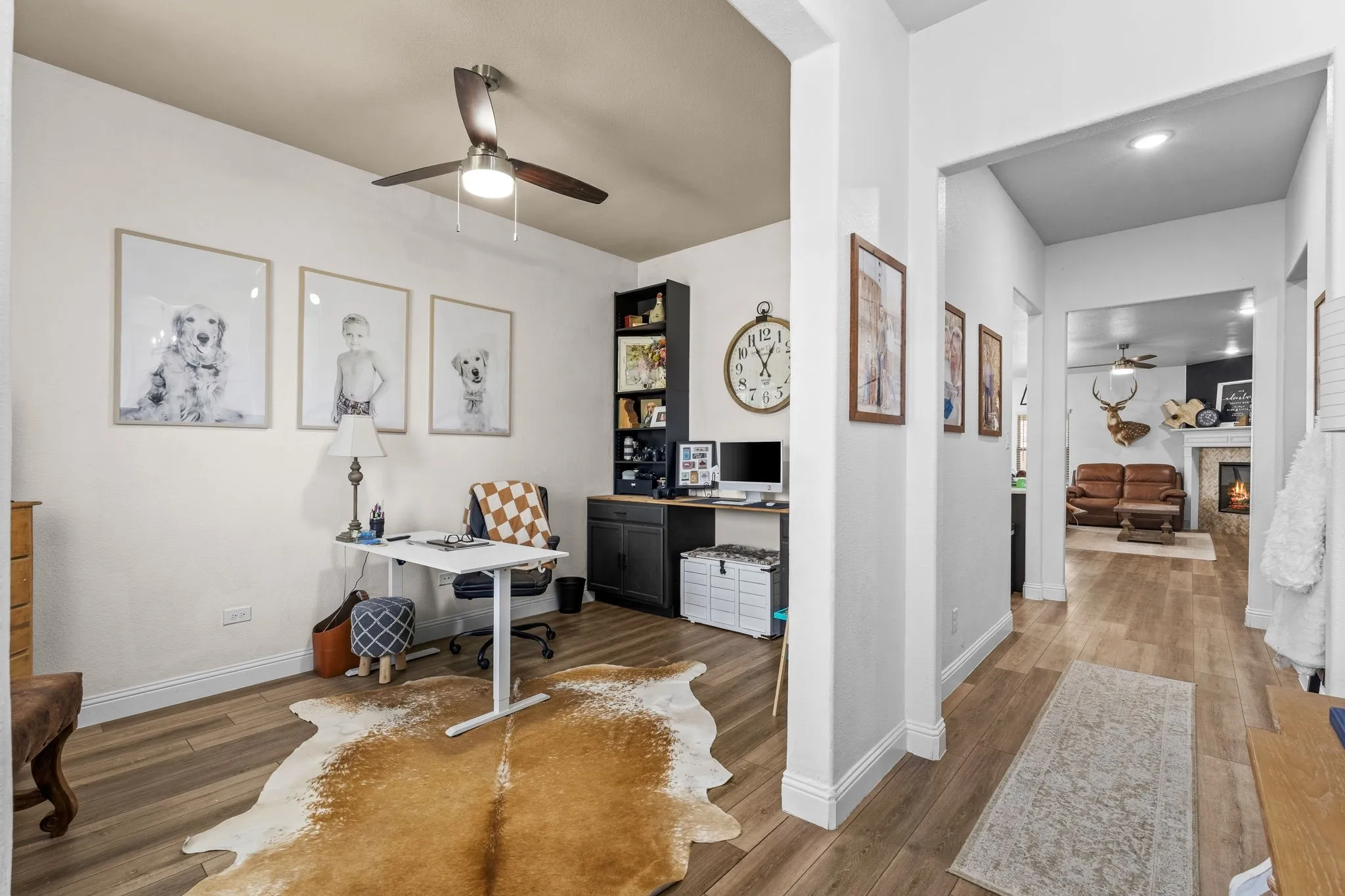 Wood-finish flooring throughout, complemented by light-toned walls and a ceiling fan with integrated lighting
