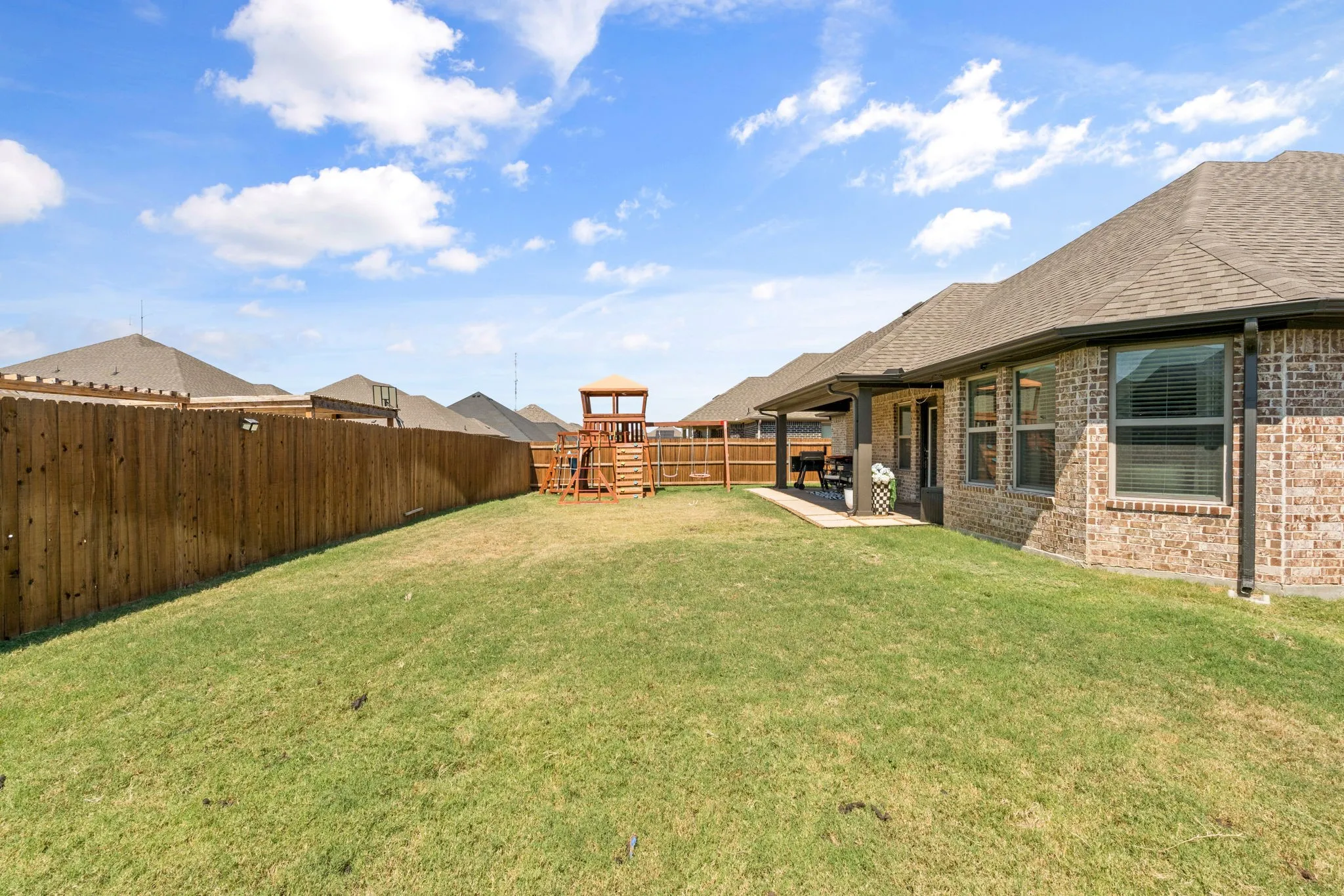 Generous rear yard with a wood privacy fence and a covered patio