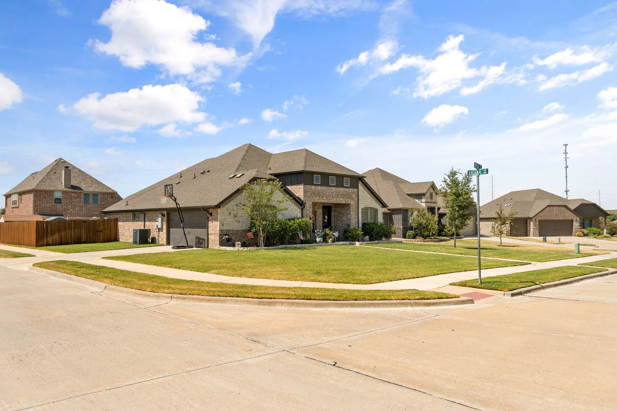 Corner lot residence featuring a brick and stone exterior, a two-car garage, and a manicured lawn