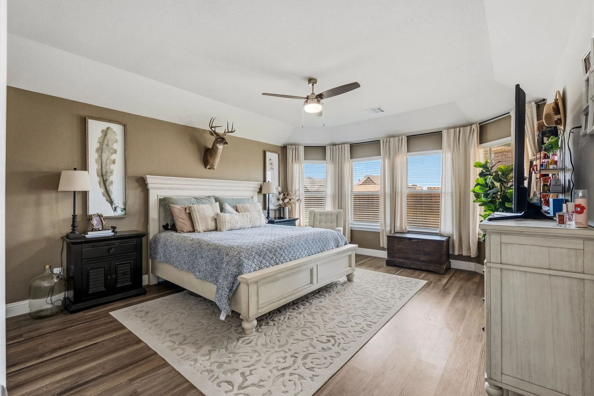 Vaulted ceiling, wood-finish flooring, ceiling fan, and a curved wall of multiple windows