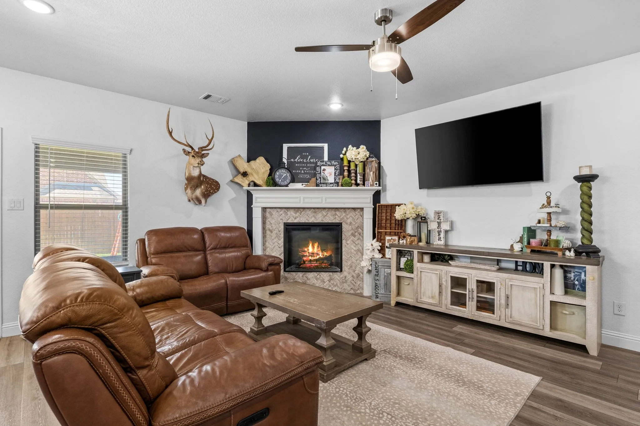 Recessed lighting, wood-finish flooring, ceiling fan, corner fireplace with stone surround and mantel, and built-in media console