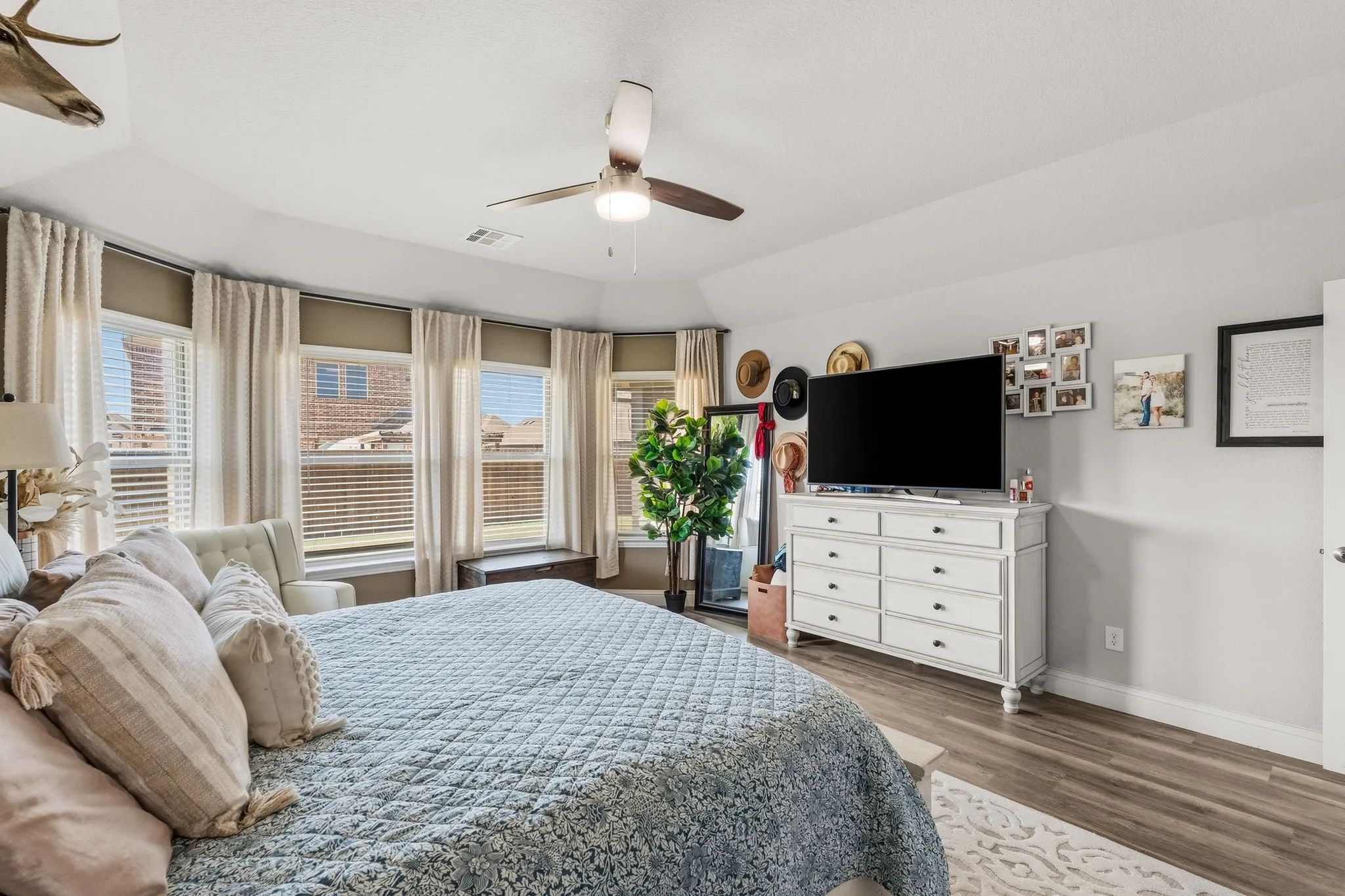 Bay window with multiple windows, wood-finish flooring, ceiling fan, and painted walls