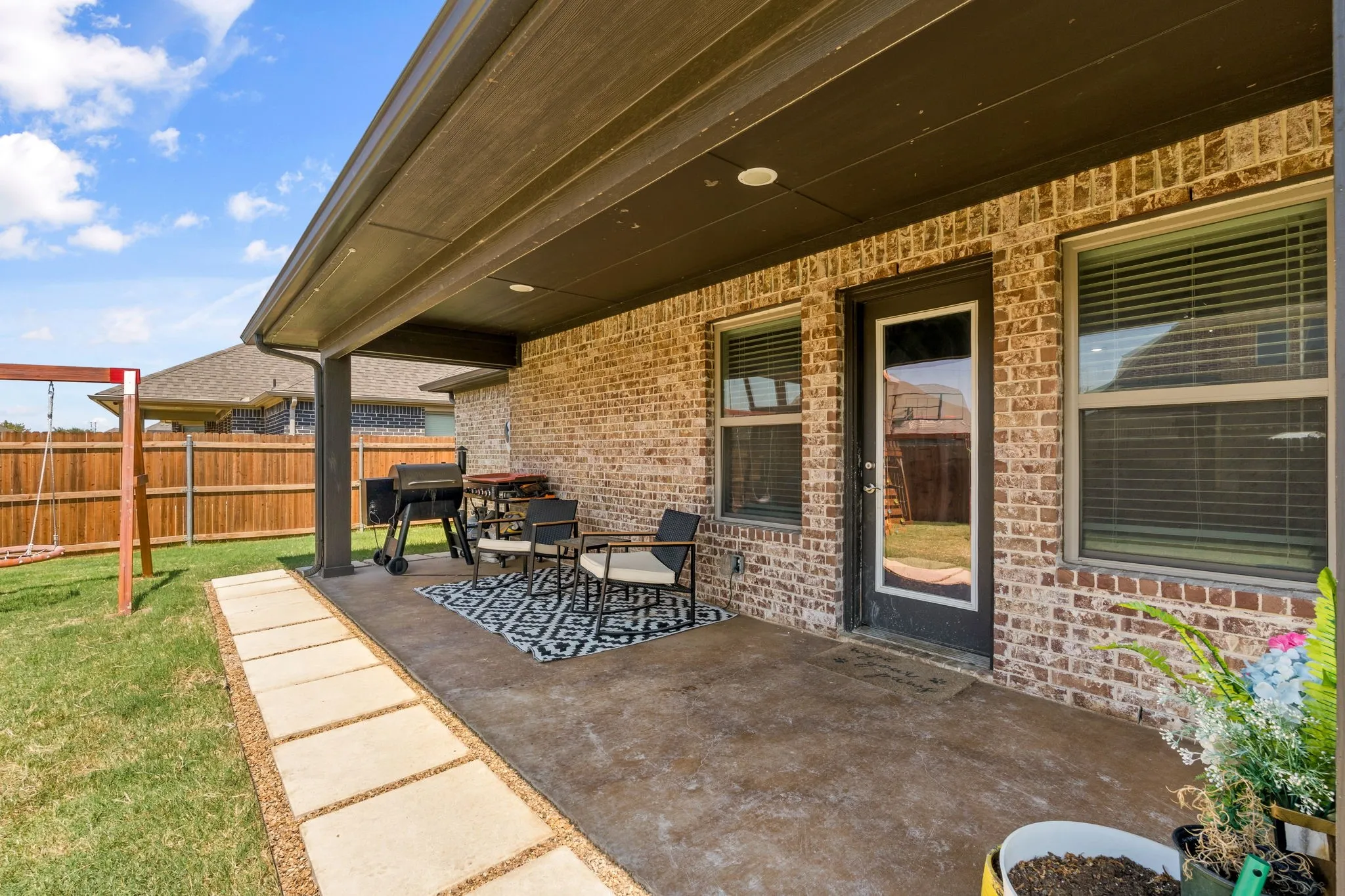 Covered patio with a concrete surface, brick exterior, and recessed lighting