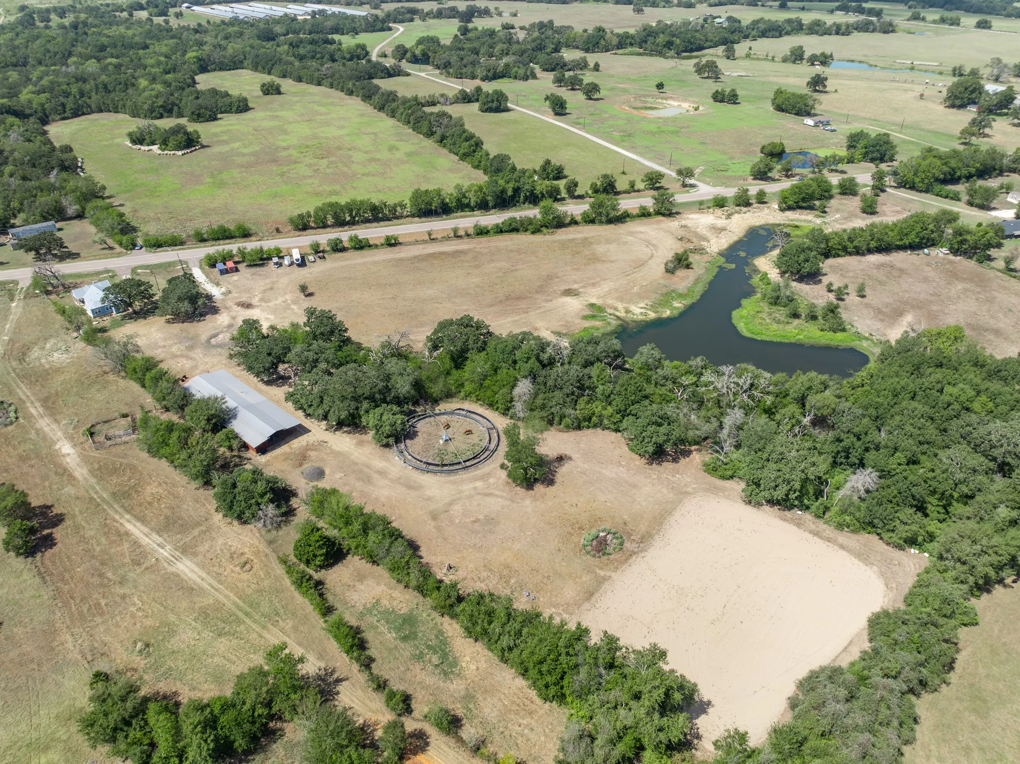 Expansive acreage featuring a barn structure, a round pen, a sand arena, and a natural pond
