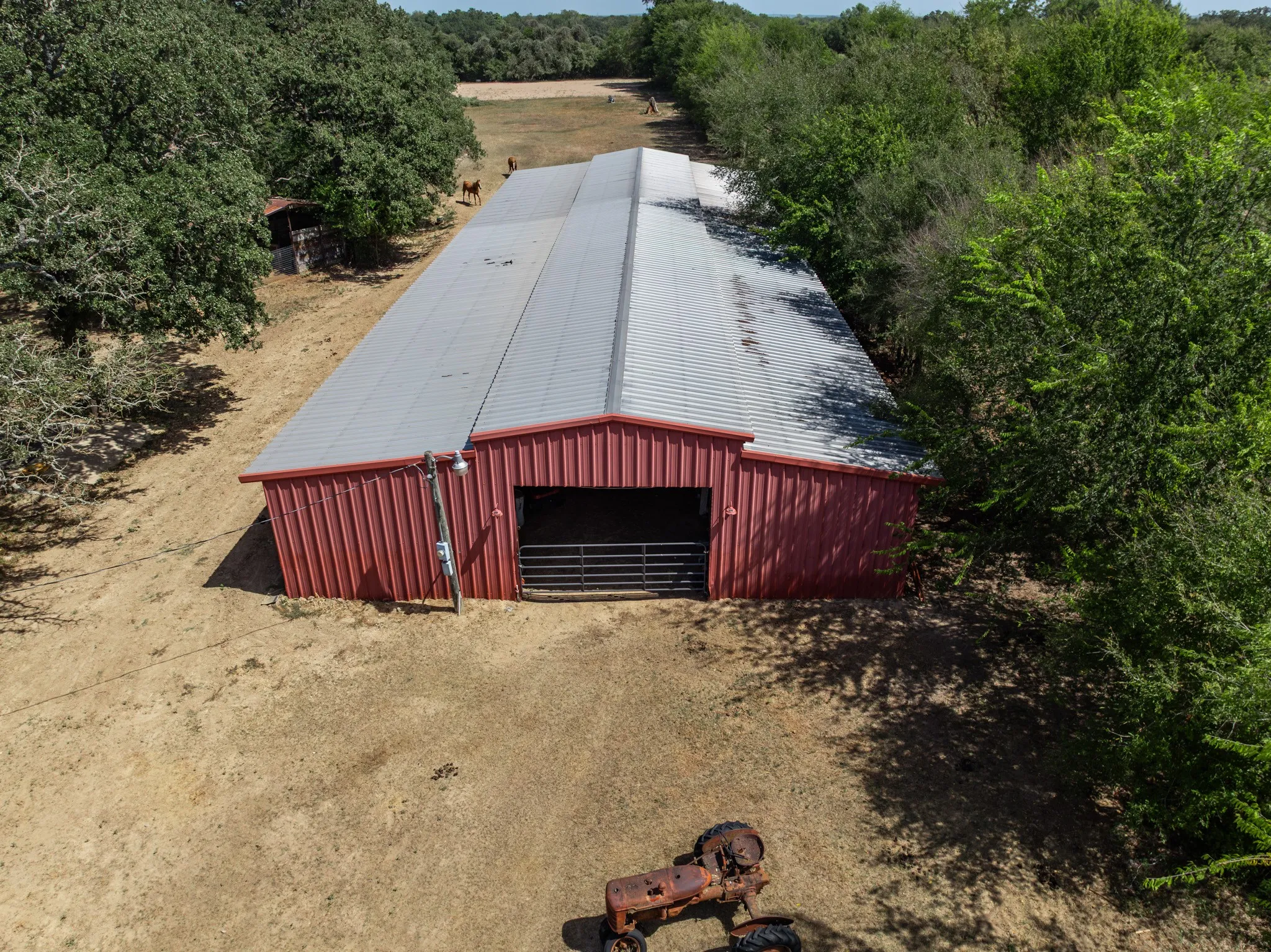 Red metal-sided barn with a grey metal roof and a large entry opening