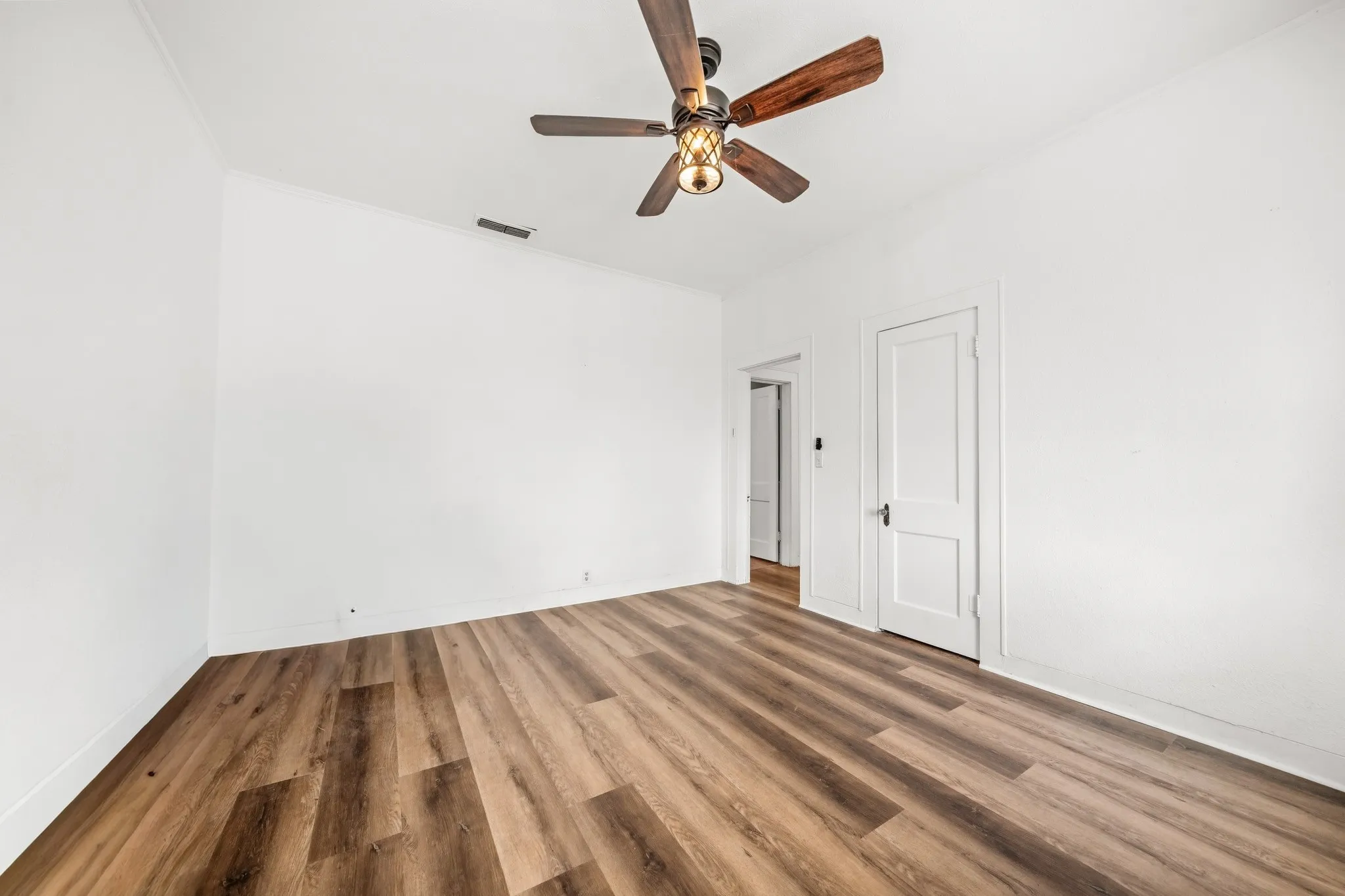 Wood-finish flooring, white walls, and a ceiling fan with light fixture