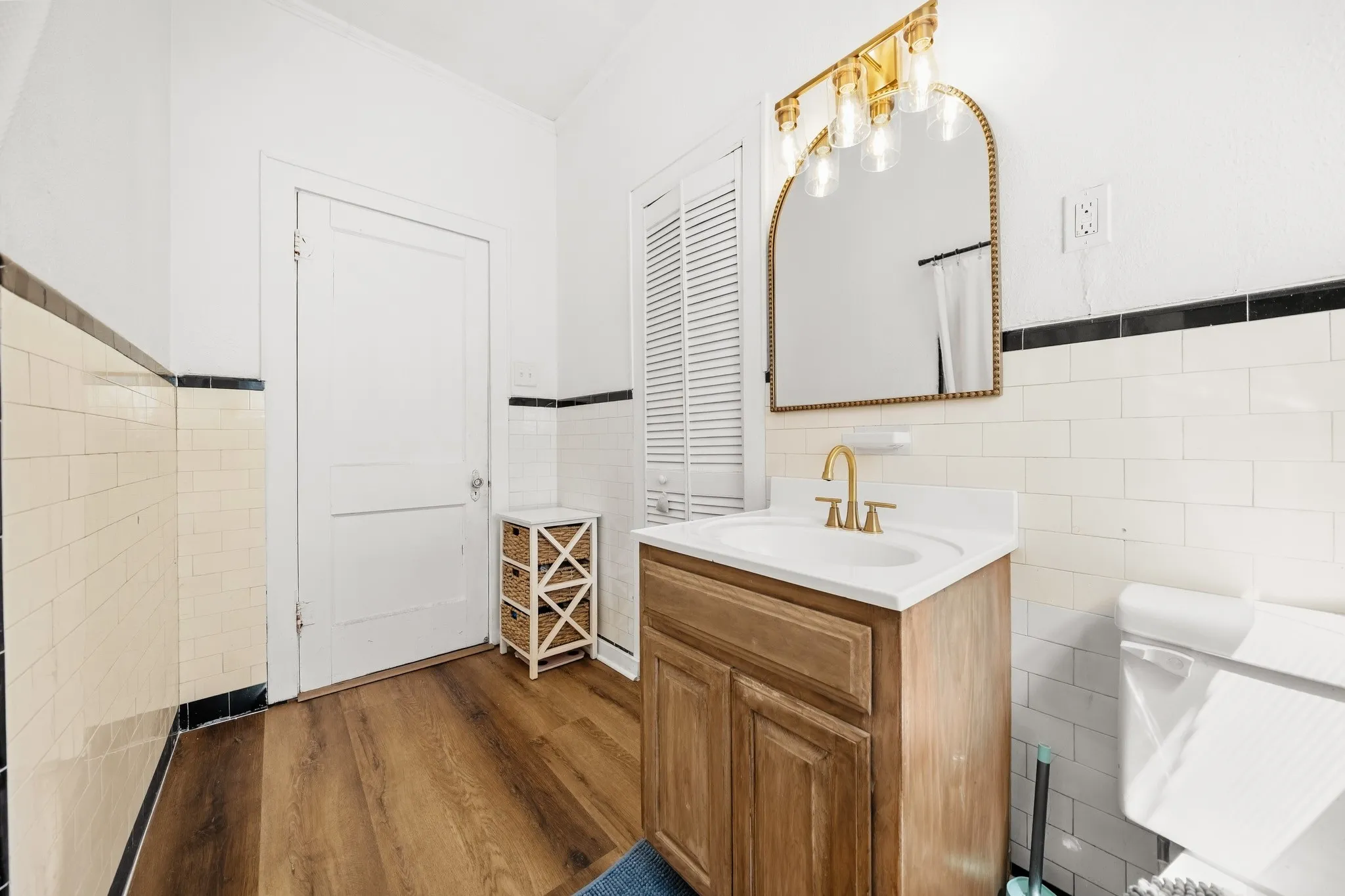 Wood-finish flooring with white and black subway tile walls