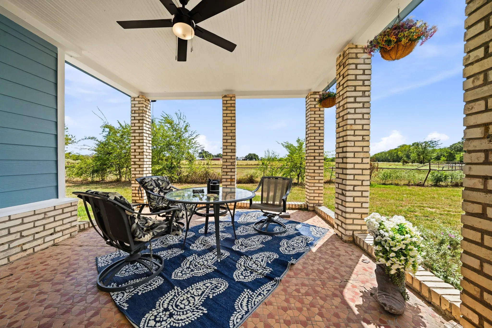 Covered porch featuring brick columns, a beadboard ceiling, and a ceiling fan