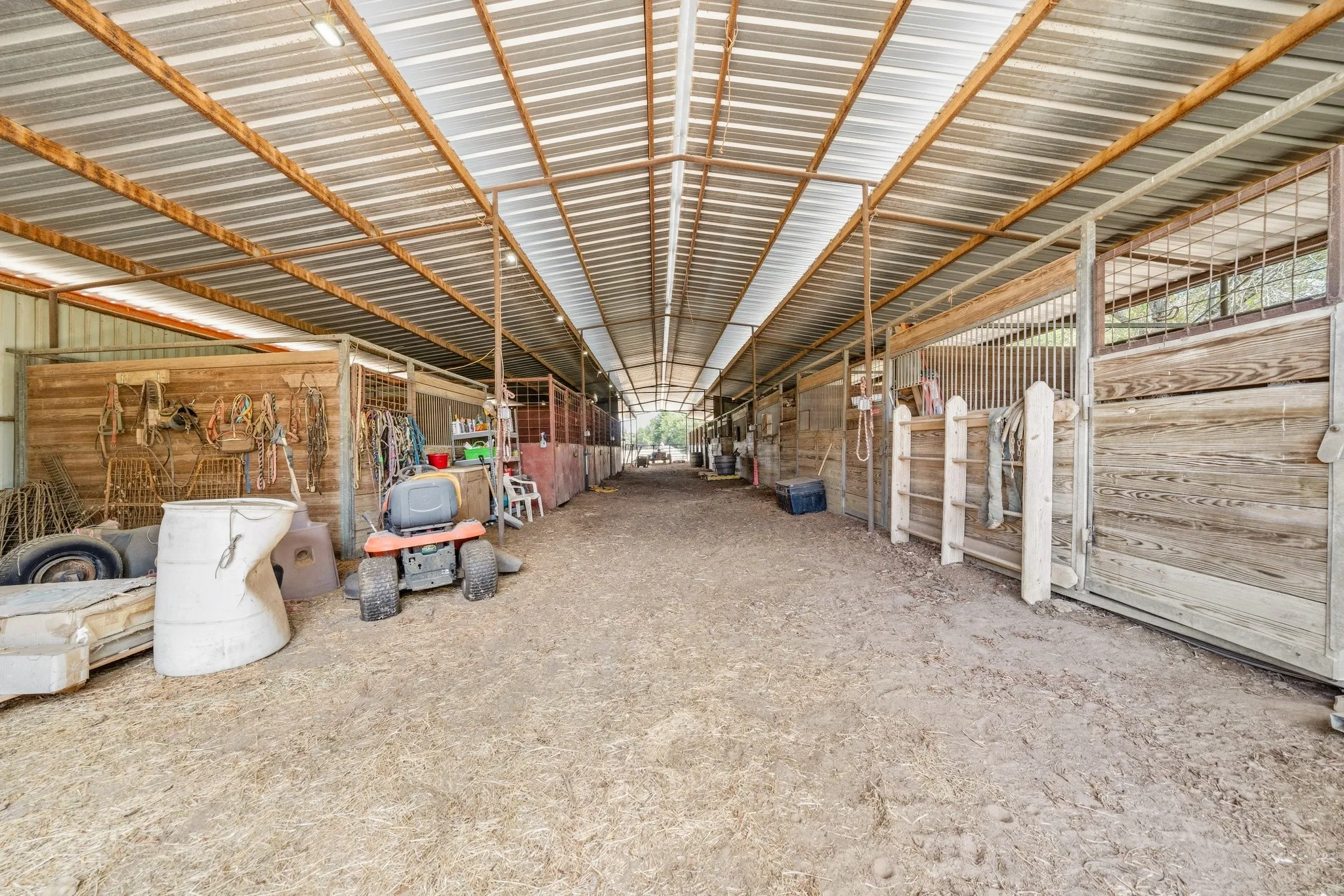 Covered stable structure featuring multiple stalls with wood-finish paneling and metal grating