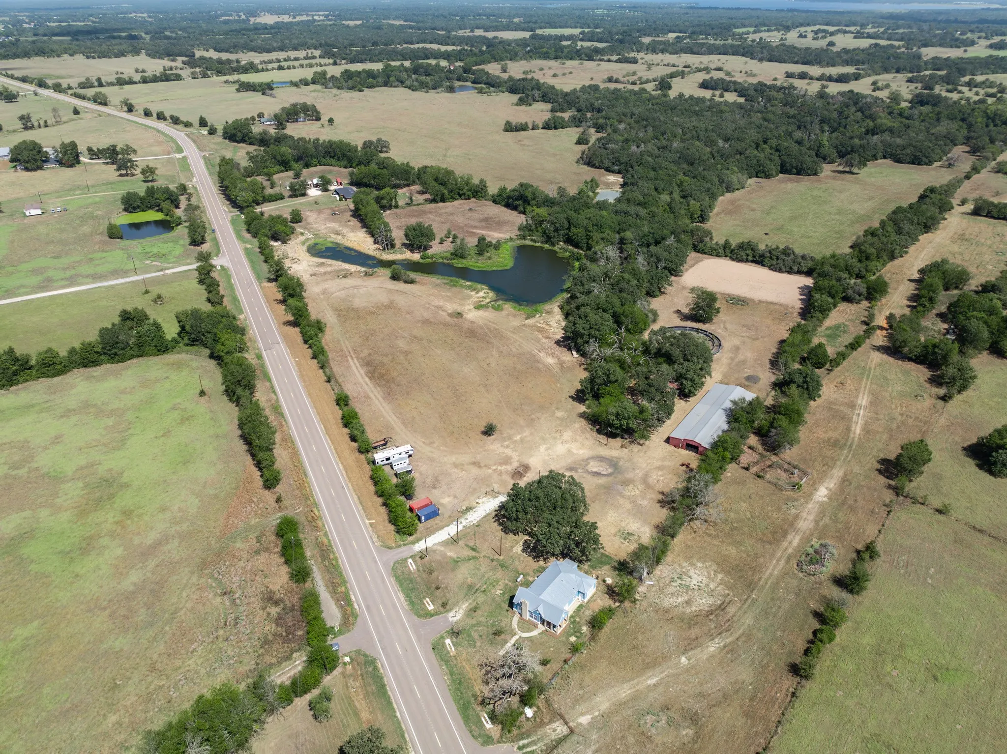 Rural landscape featuring a paved road, multiple bodies of water, and extensive open fields