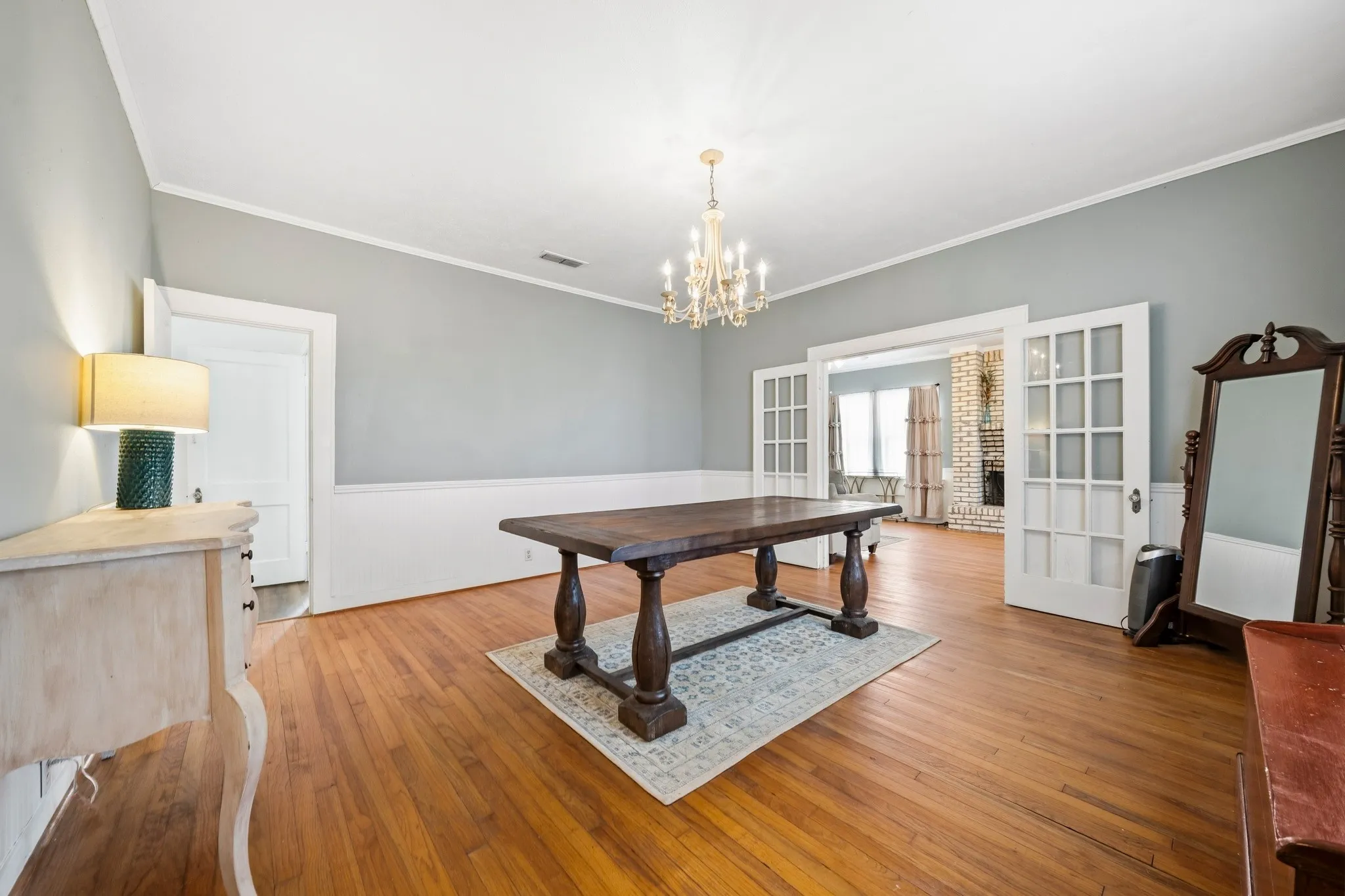 Hardwood flooring, crystal chandelier, double French doors, wainscoting, and crown molding