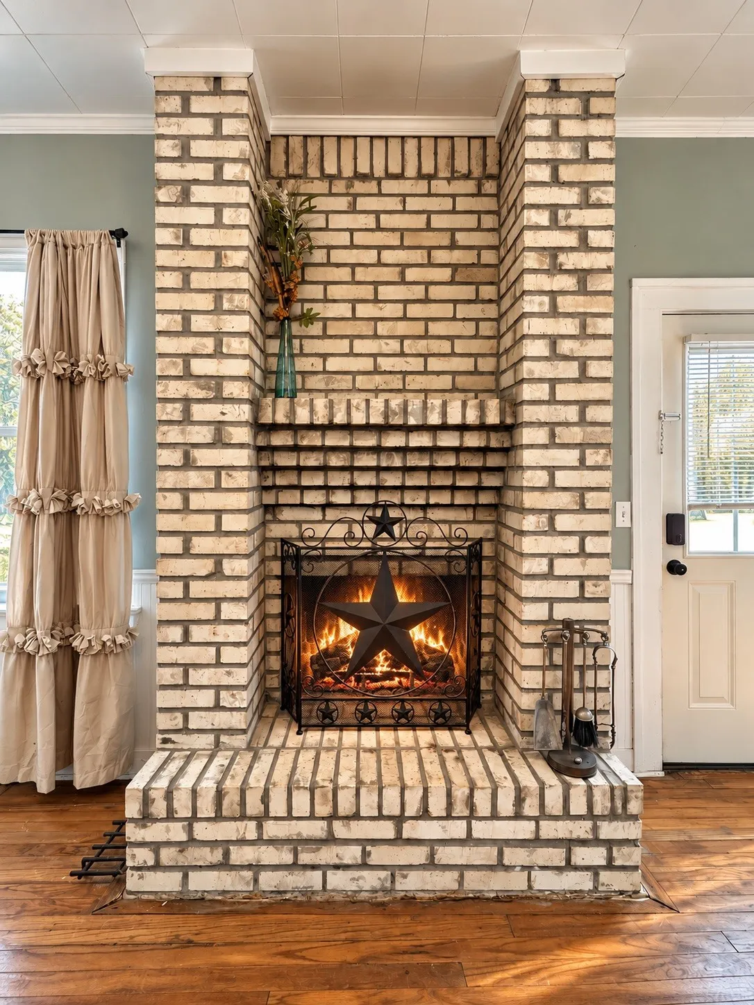 Brick fireplace with a substantial hearth, wood-finish flooring, and crown molding