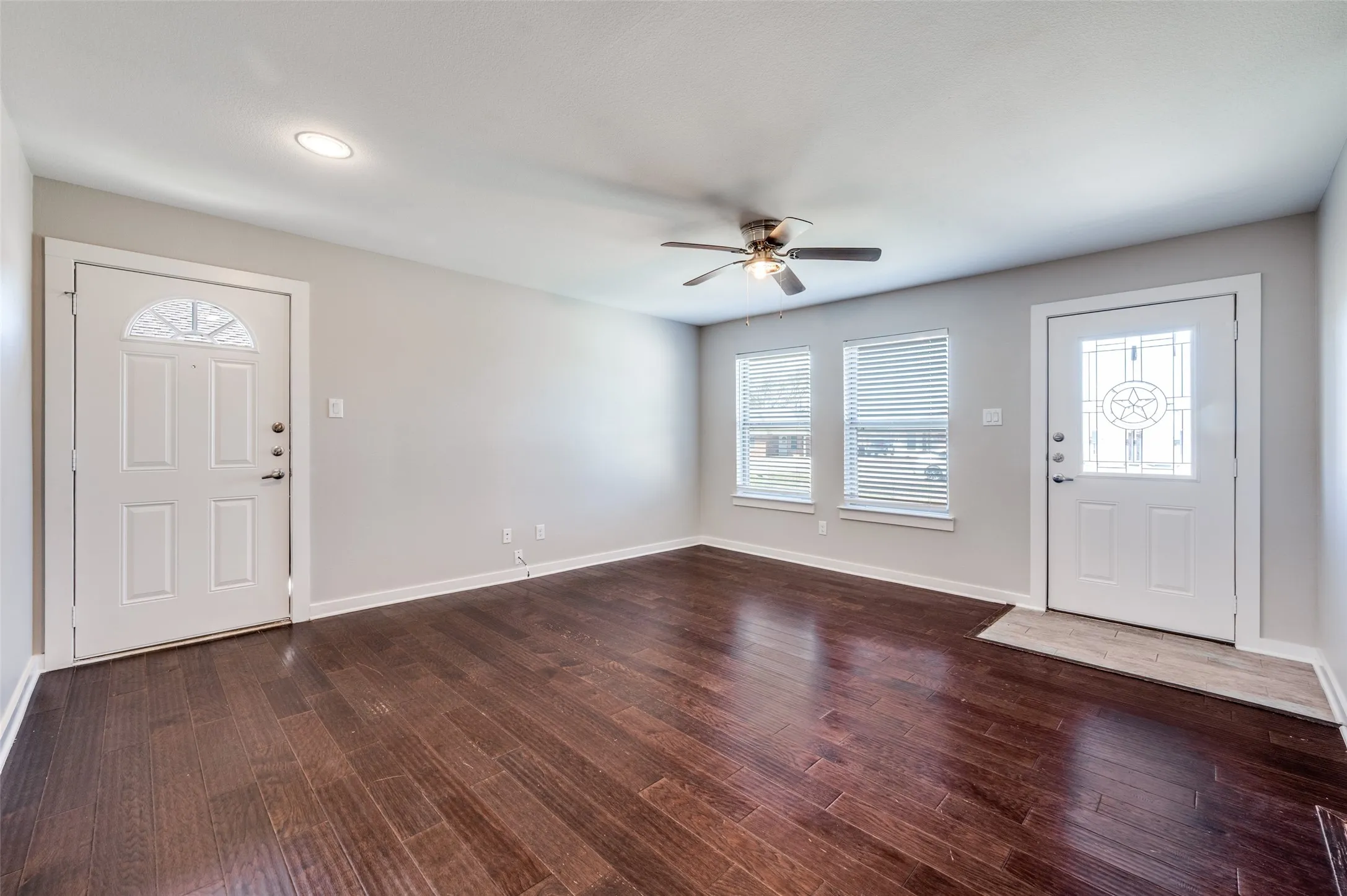 Spacious room featuring wood-finish flooring, a ceiling fan, recessed lighting, and multiple windows