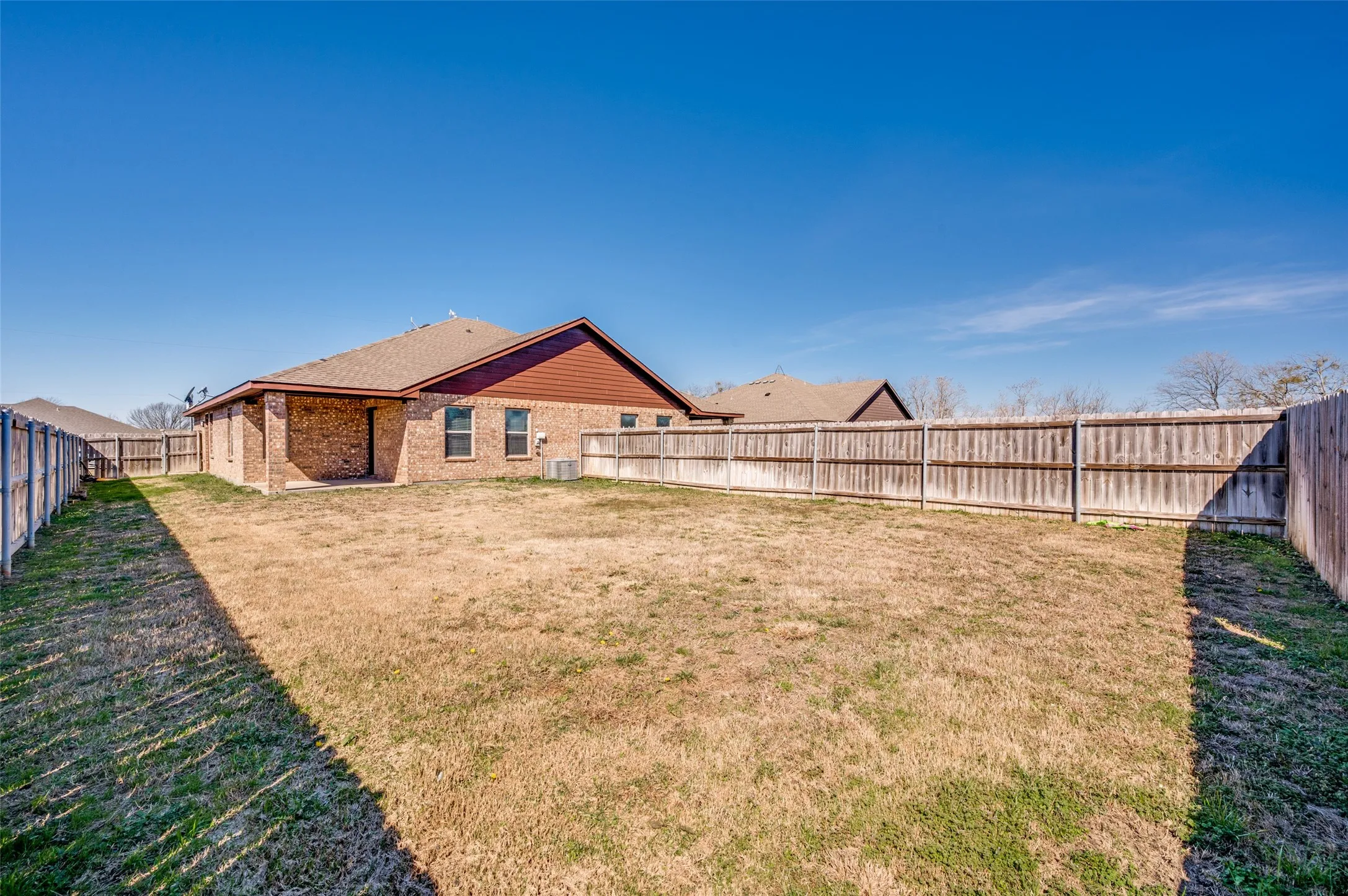 Expansive backyard featuring a privacy fence and a covered patio