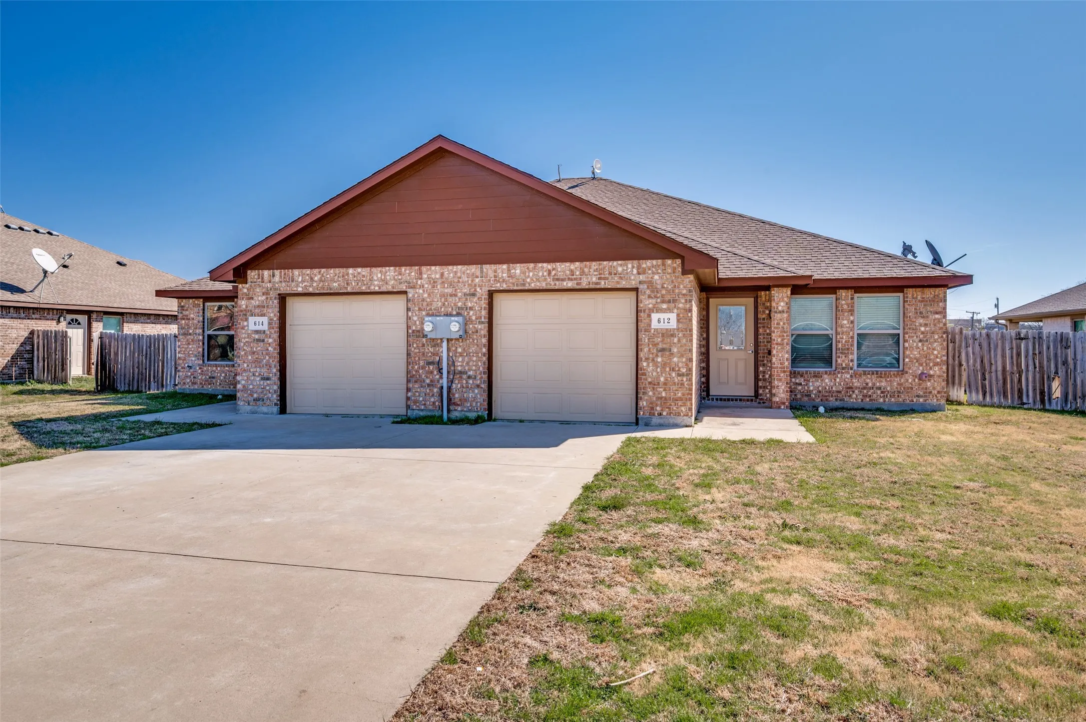 Brick exterior with a brown gable, two single-car garages, and a concrete driveway