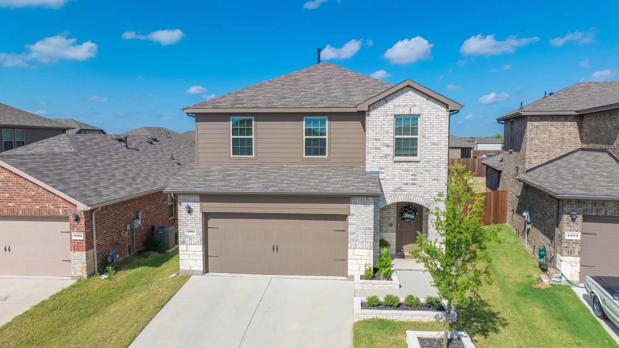 Two-story residence featuring a combination of brick and siding, an arched entryway, and an attached two-car garage