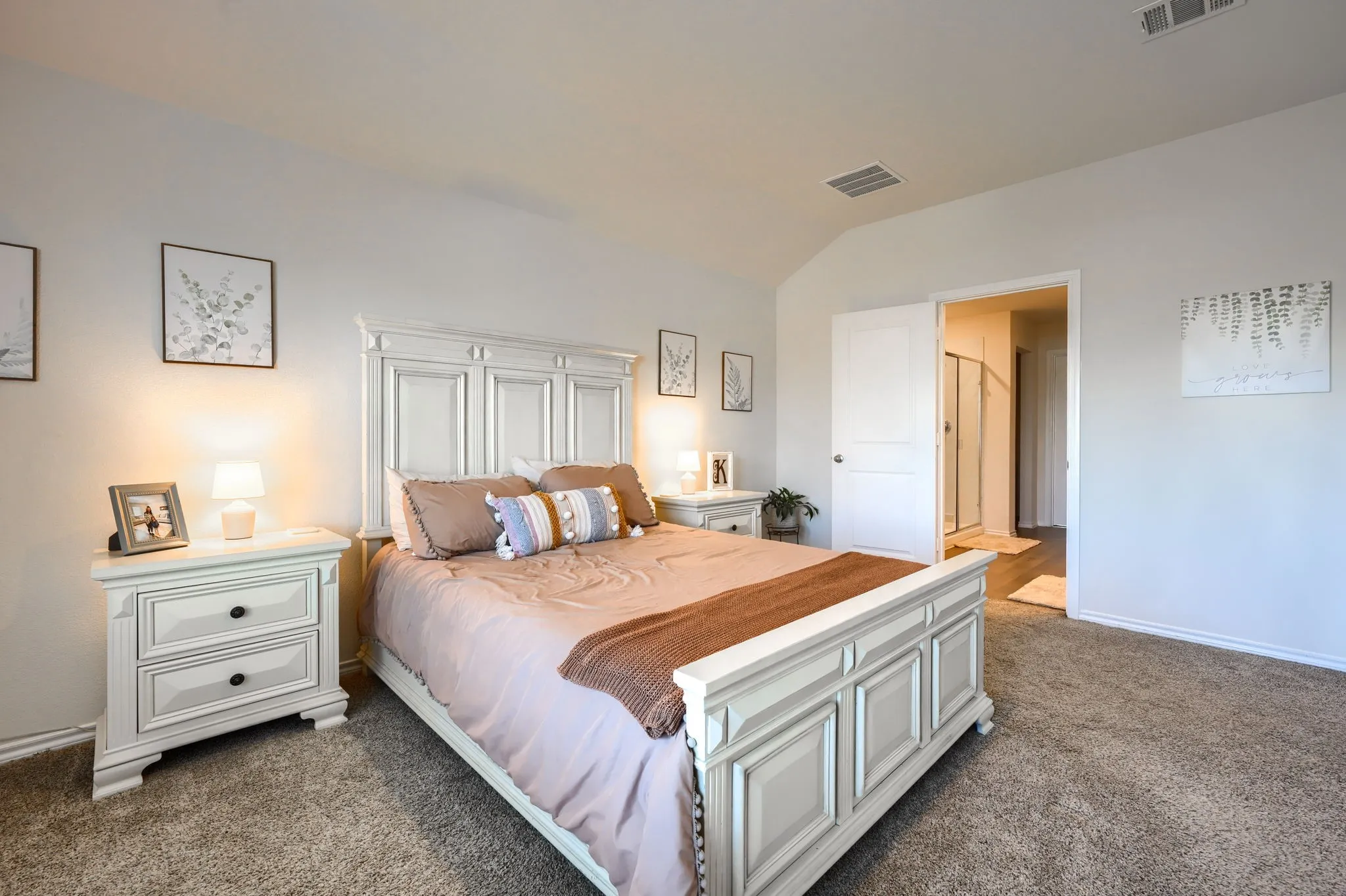 Vaulted ceiling, neutral wall paint, carpet flooring, paneled interior doors, and a partial bathroom entry