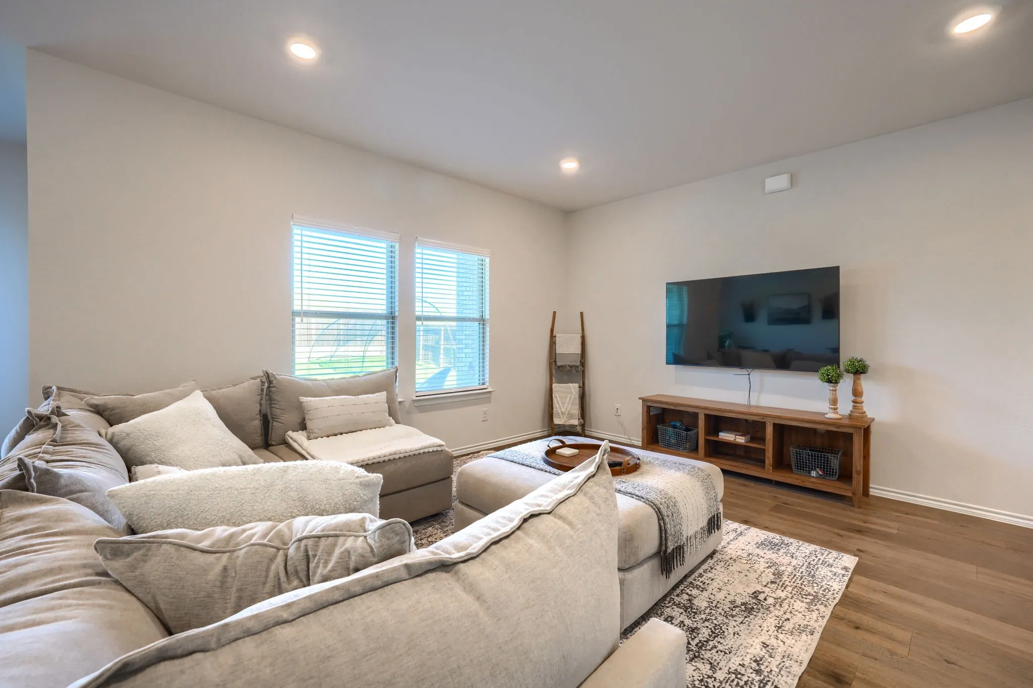 Recessed lighting, wood-finish flooring, and white window blinds