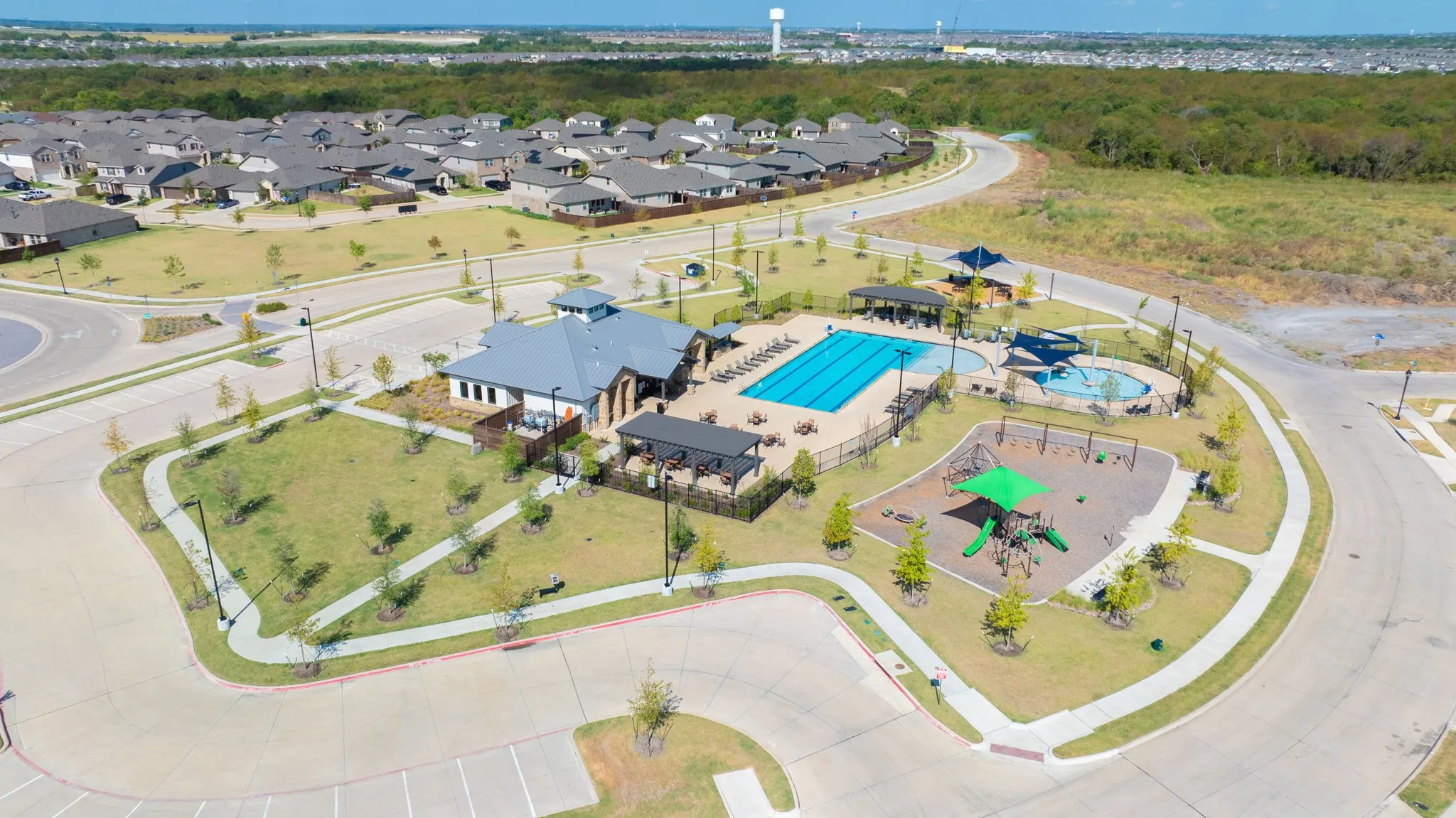 Community amenity center featuring a swimming pool, separate children's water play area, and a playground