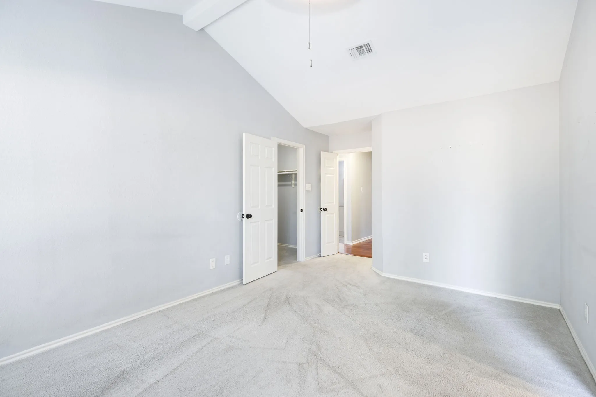 Vaulted ceiling with ceiling fan, carpet flooring, and white interior doors