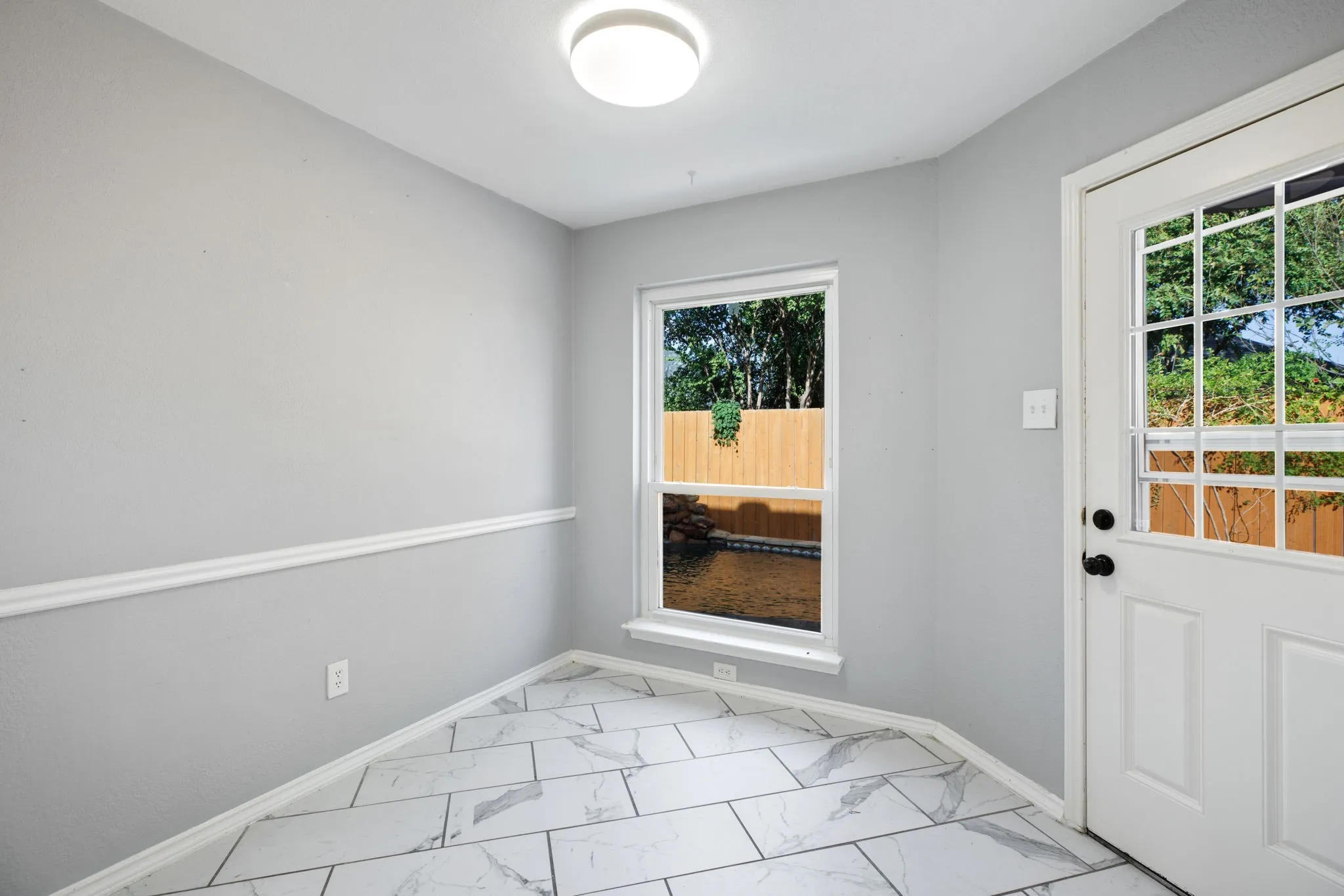 Recessed lighting, tile flooring, window with exterior landscape, chair rail molding, and a paneled exterior door