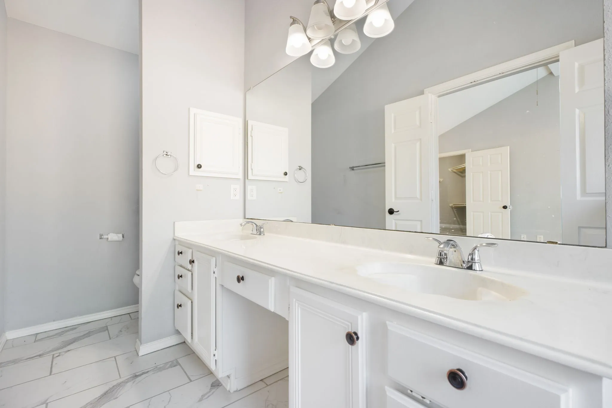 Dual vanity with white cabinetry and integrated sinks, extensive countertop space, wall-mounted mirror, and tile flooring