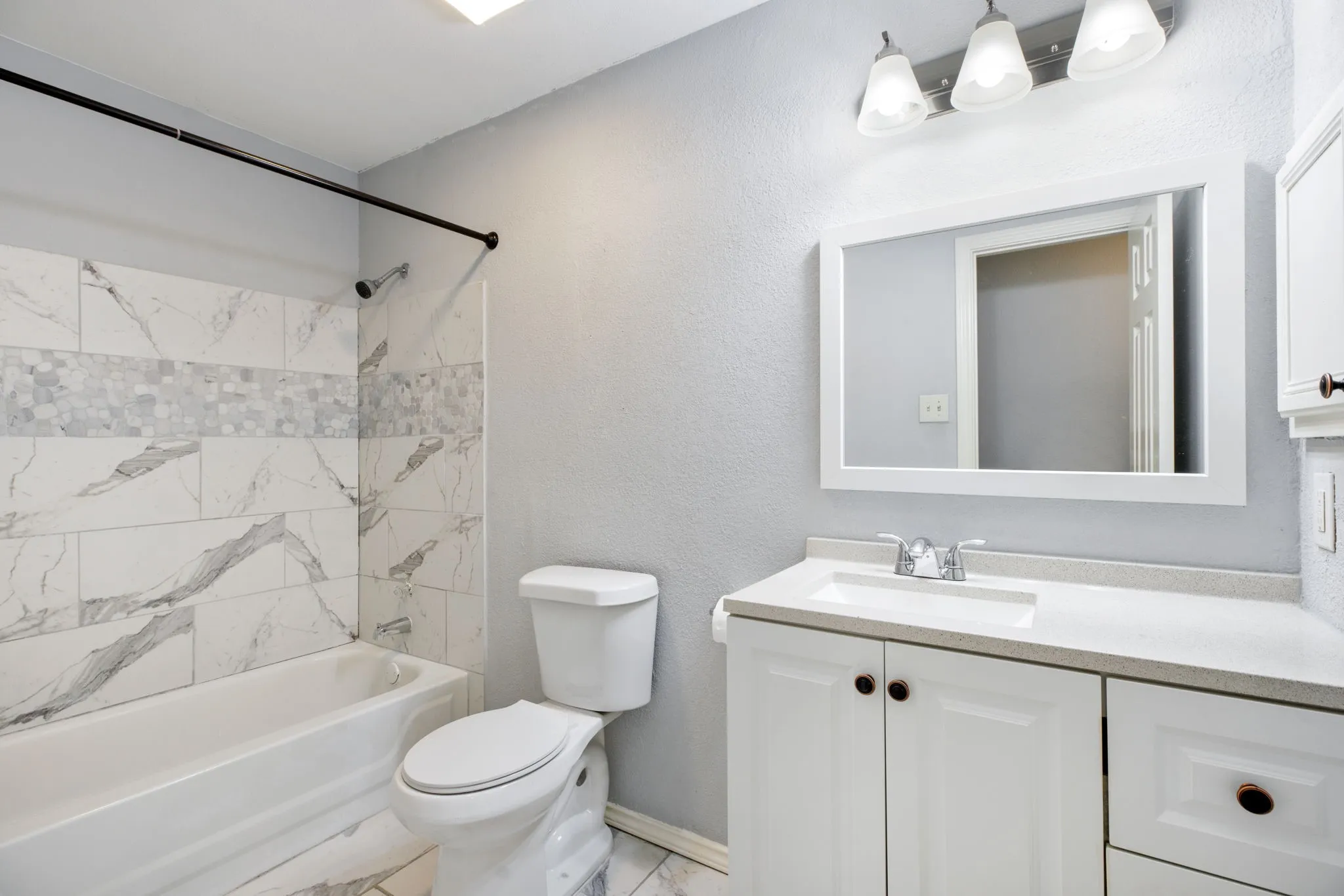White vanity with a light-colored countertop, undermount sink, and chrome fixtures