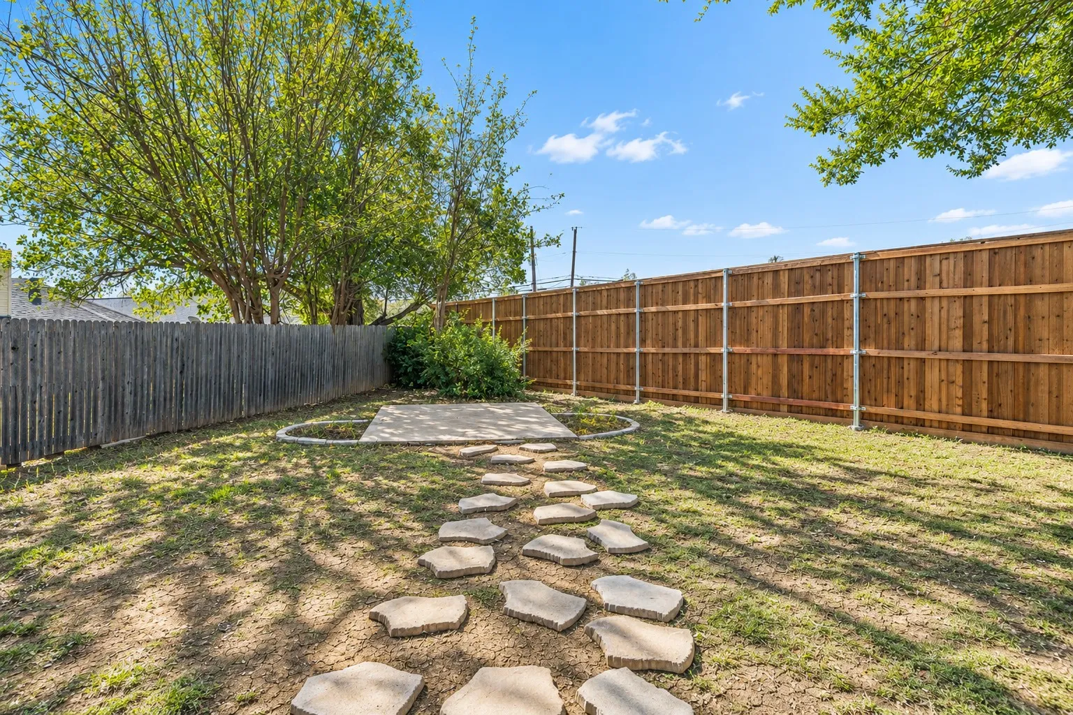 Private fenced yard featuring a concrete patio and stepping stone pathway