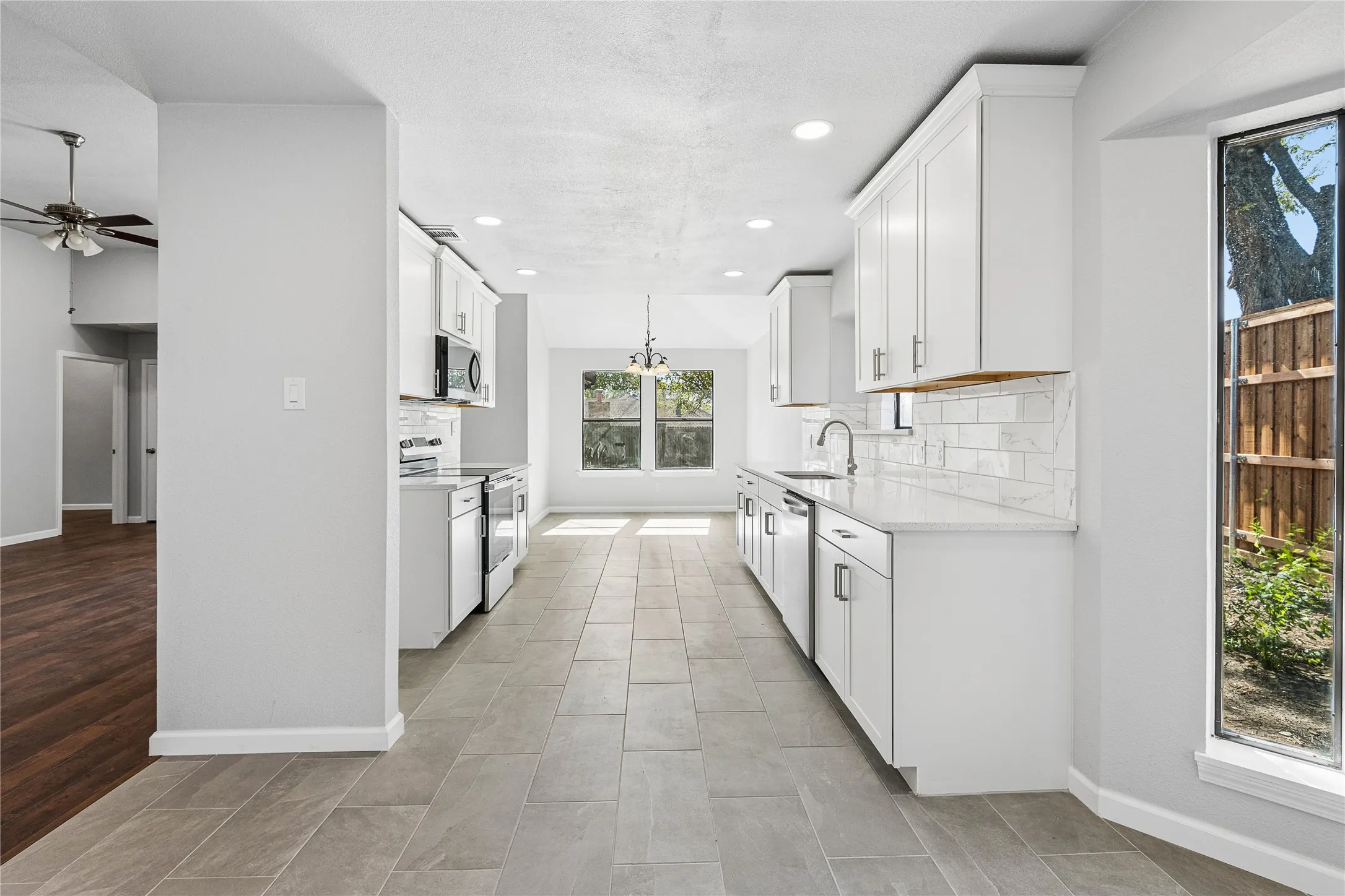 Contemporary kitchen featuring white cabinetry, stainless steel appliances, a subway tile backsplash, and light-toned tile flooring