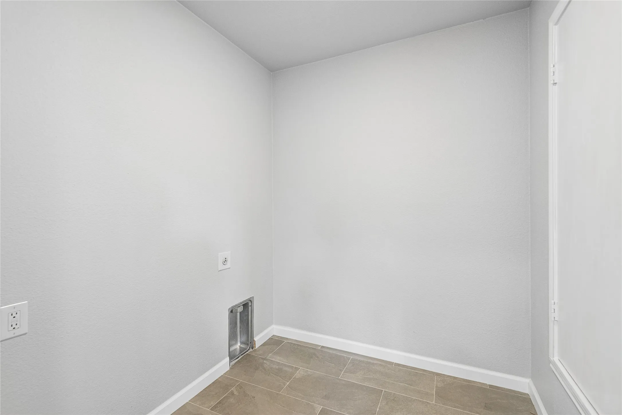 Light gray wall paint with white trim, wood-look tile flooring, and utility hookups