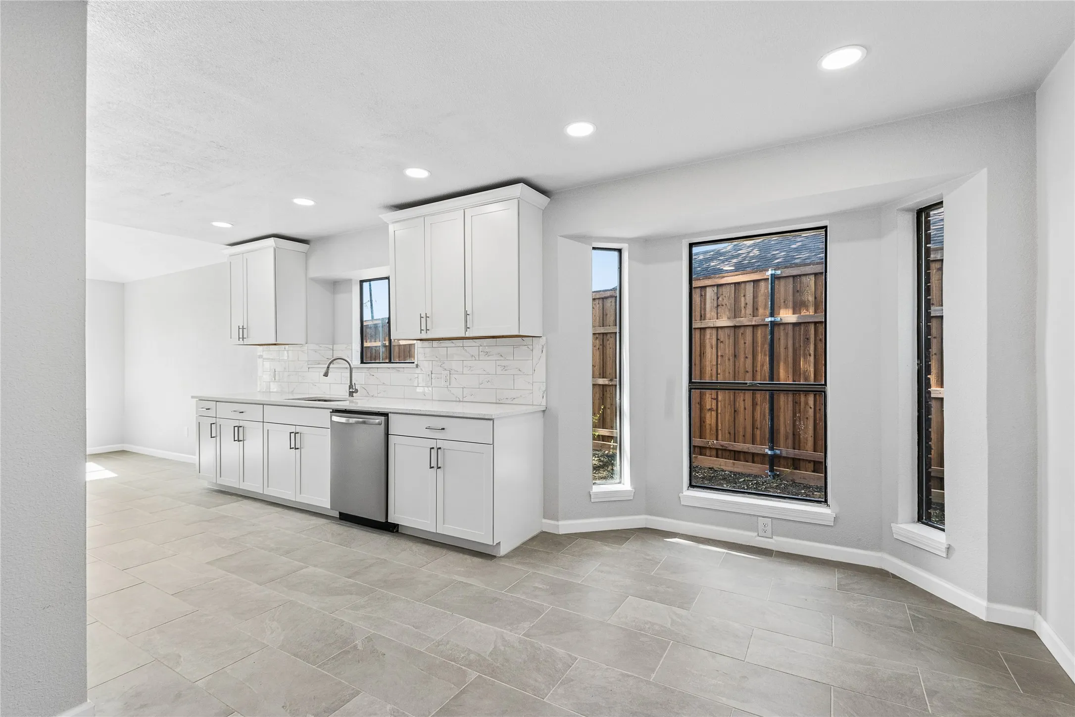 Recessed lighting illuminates the space, showcasing white shaker cabinetry, an undermount sink, and stainless steel appliances