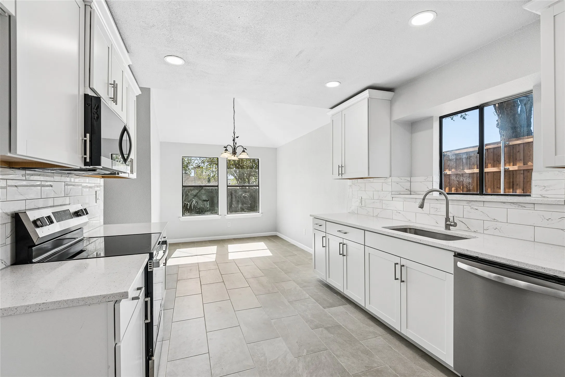 Kitchen featuring white cabinetry, light-toned countertops, subway tile backsplash, stainless steel appliances, and tile flooring