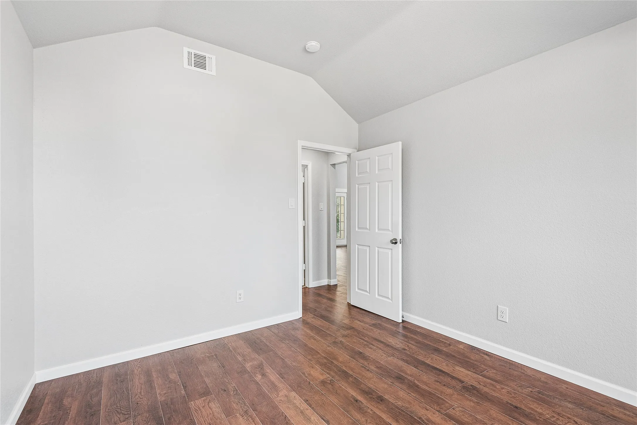 Wood-finish flooring, vaulted ceiling, and paneled interior door