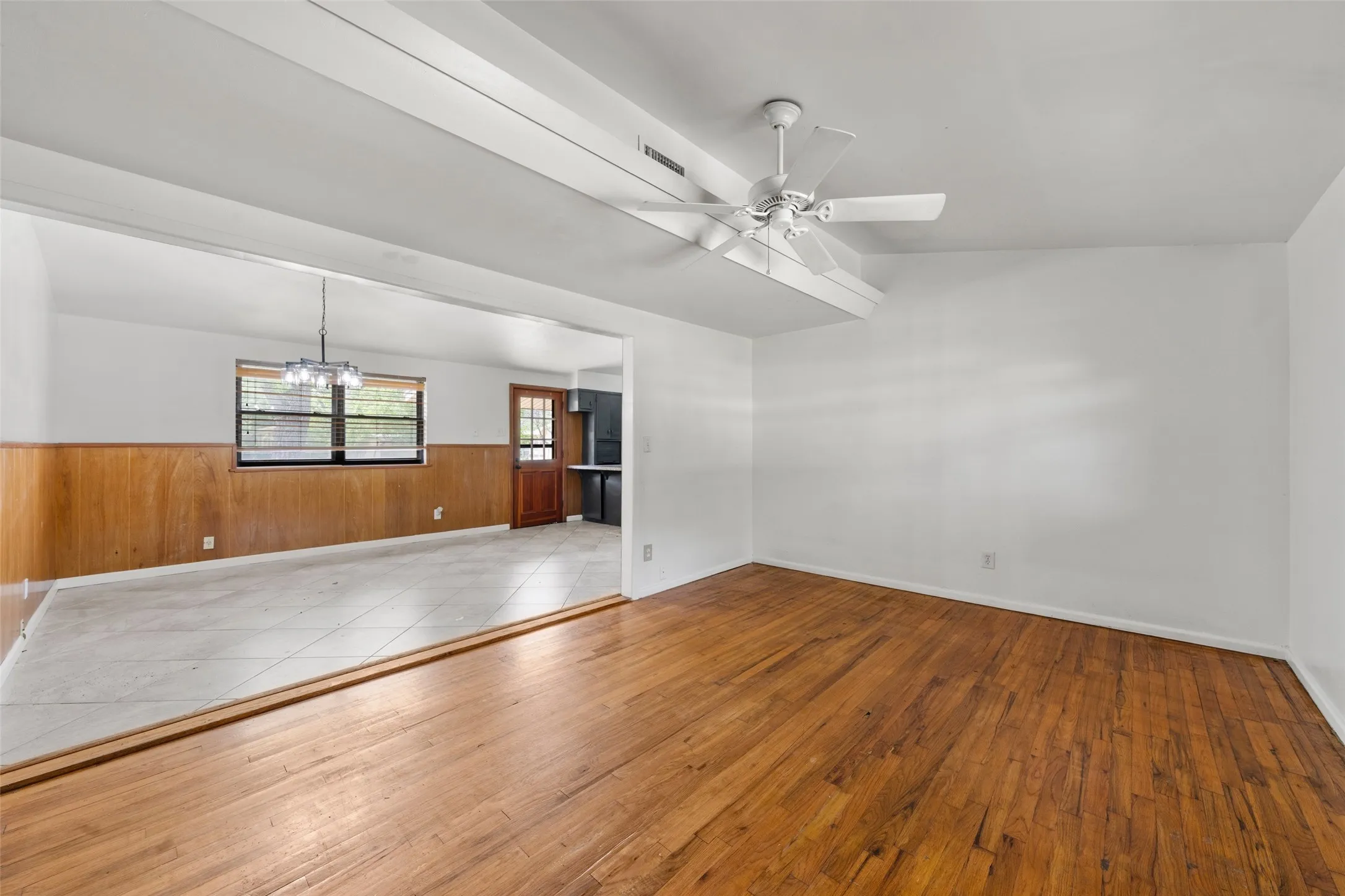 Wood-finish flooring, white walls, and a ceiling fan in the foreground