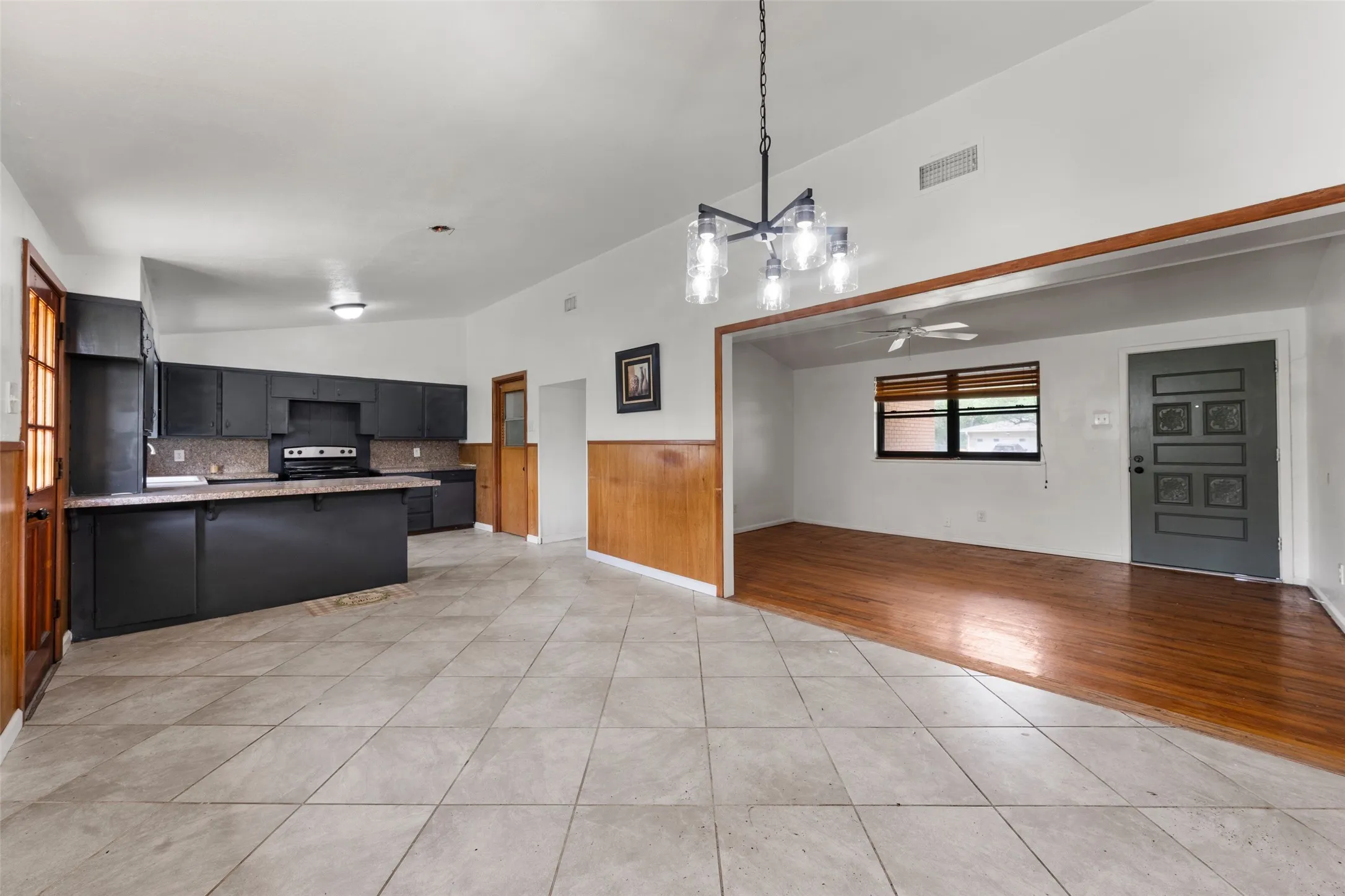 Open concept kitchen and living area featuring dark cabinetry, a tile backsplash, and a central island