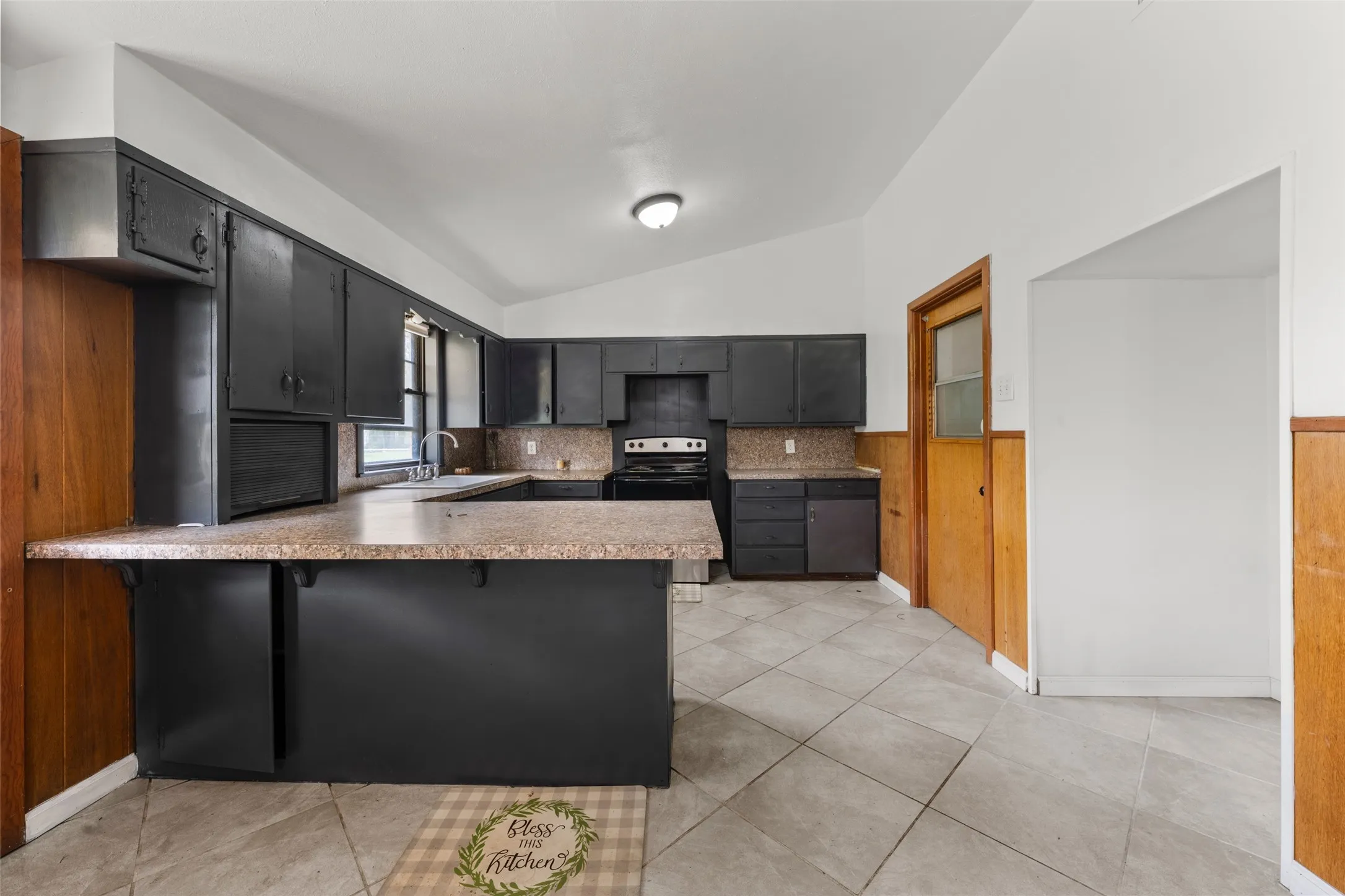 Kitchen featuring dark cabinetry, light-toned countertops, a built-in sink, and tile flooring