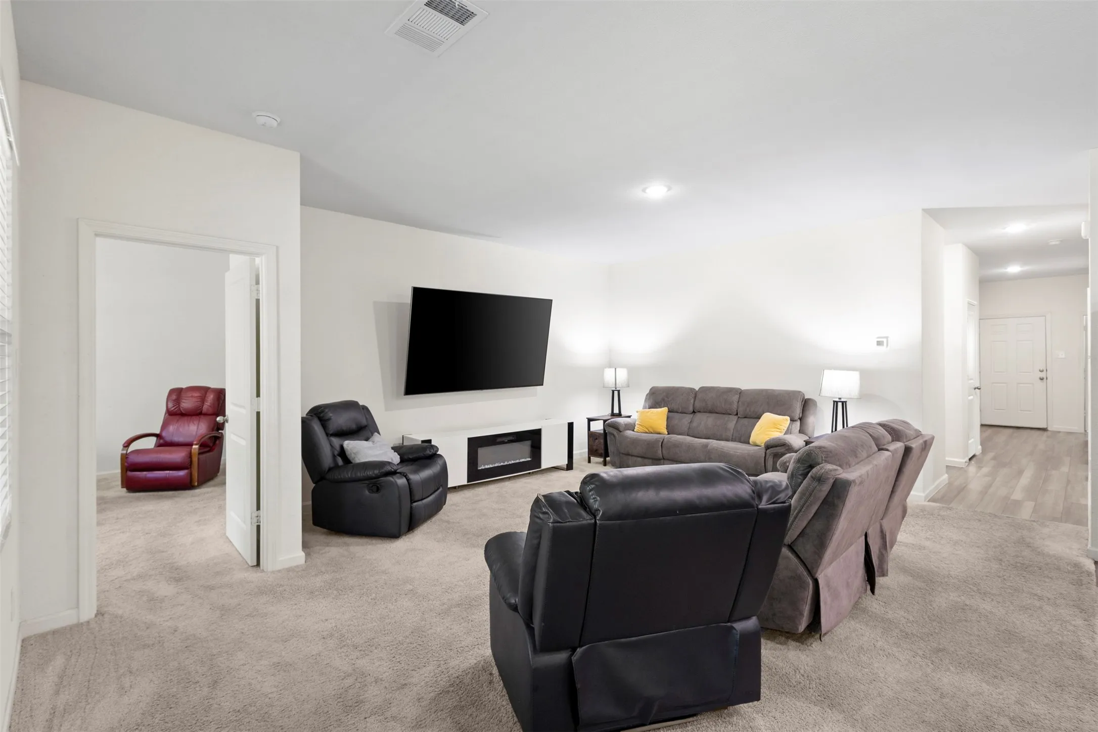 Spacious living area featuring neutral carpeting, recessed lighting, and a built-in media console with an electric fireplace