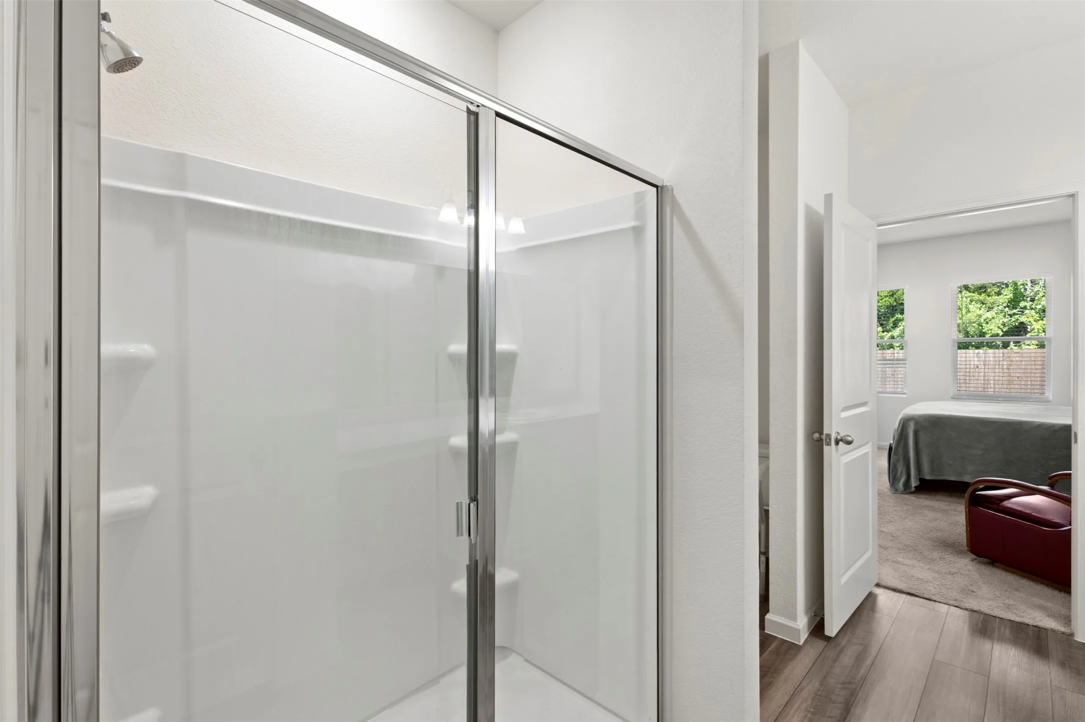 Modern ensuite bathroom featuring a frameless glass shower enclosure with chrome hardware, tile surround, and integrated showerhead