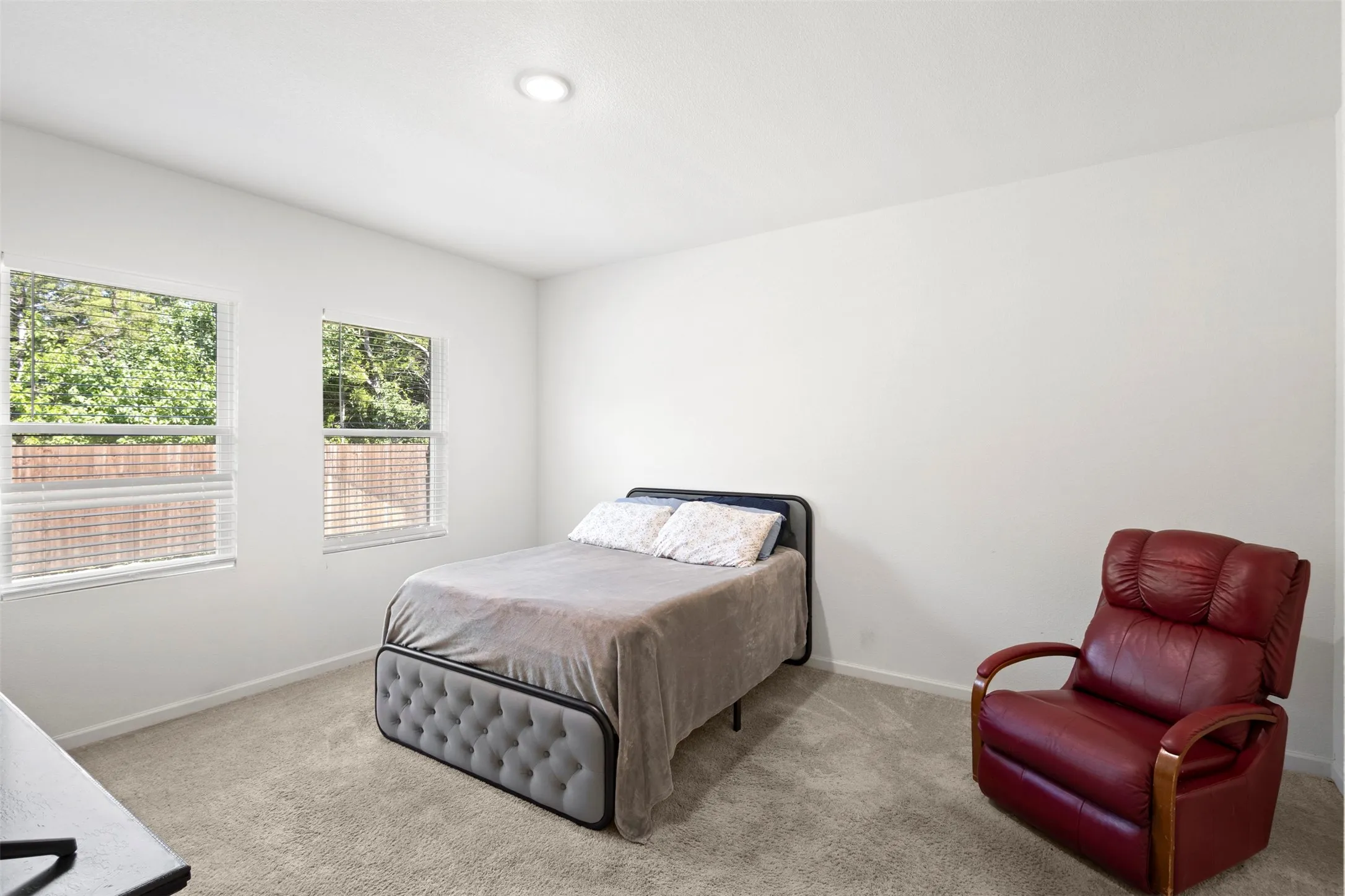 Neutral wall color, recessed ceiling lighting, two windows with blinds, and carpeted flooring