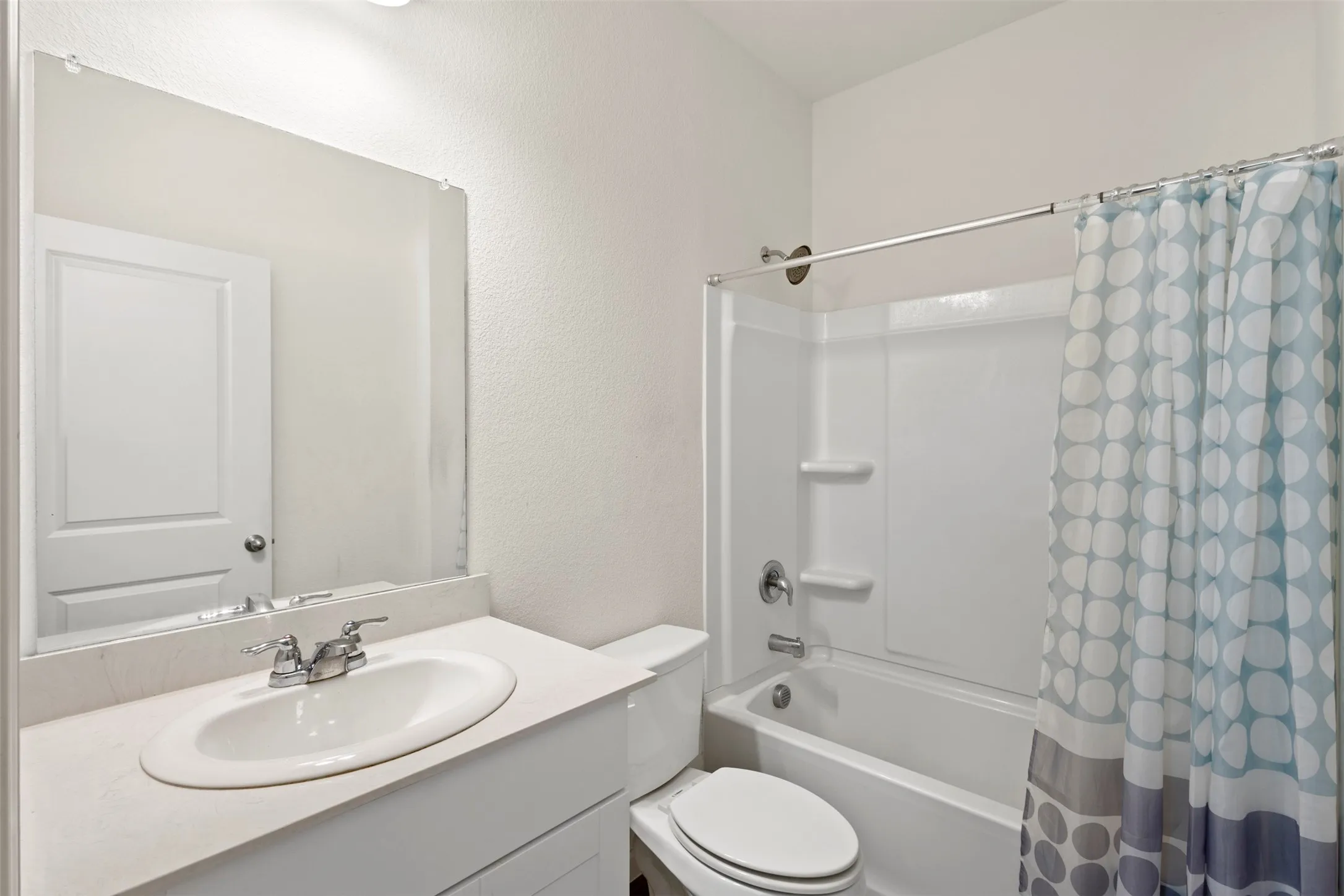 White vanity with integrated sink, chrome faucet, and expansive mirror