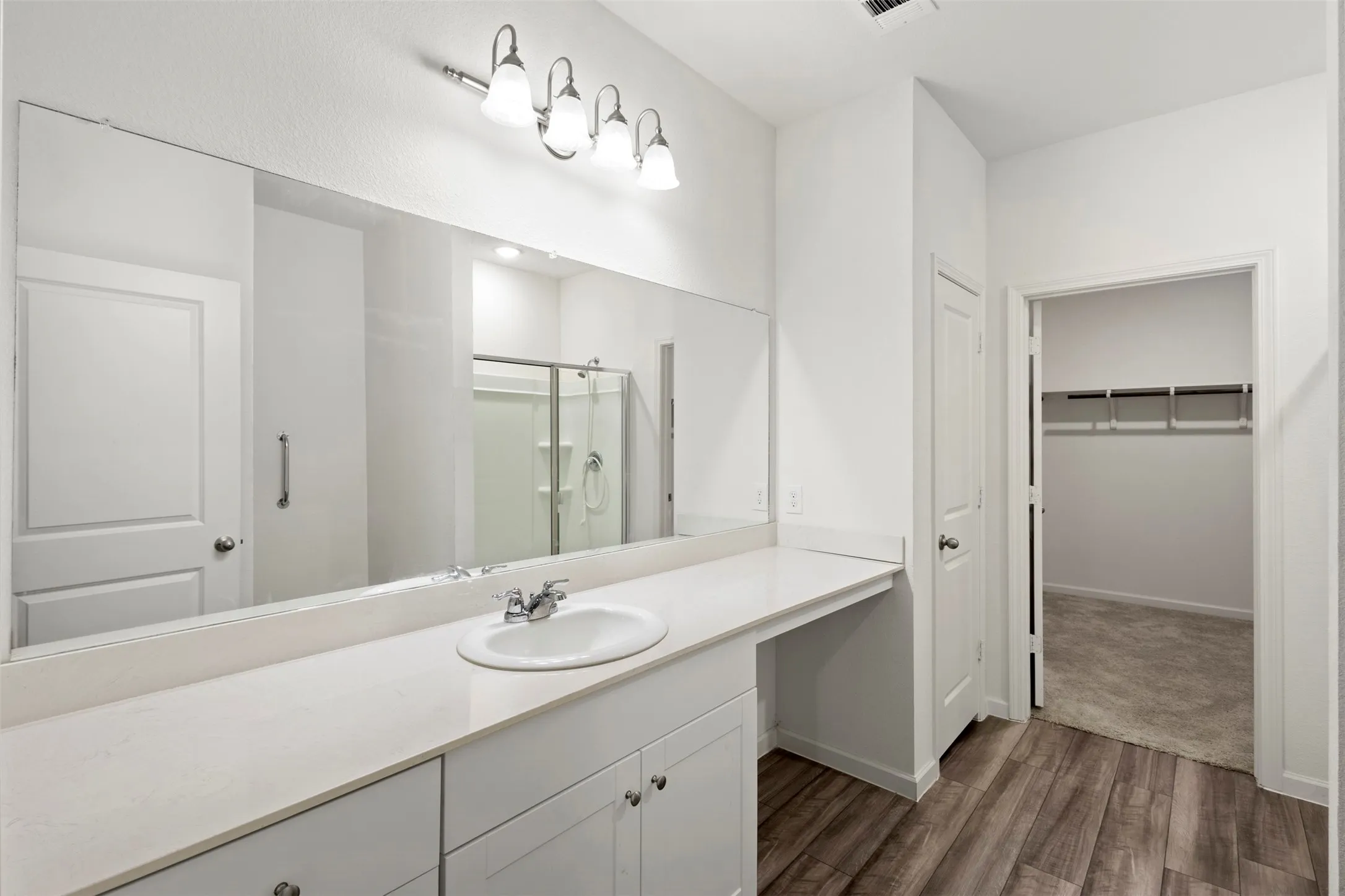 Integrated vanity with an undermount sink, expansive wall-mounted mirror, and overhead lighting fixture