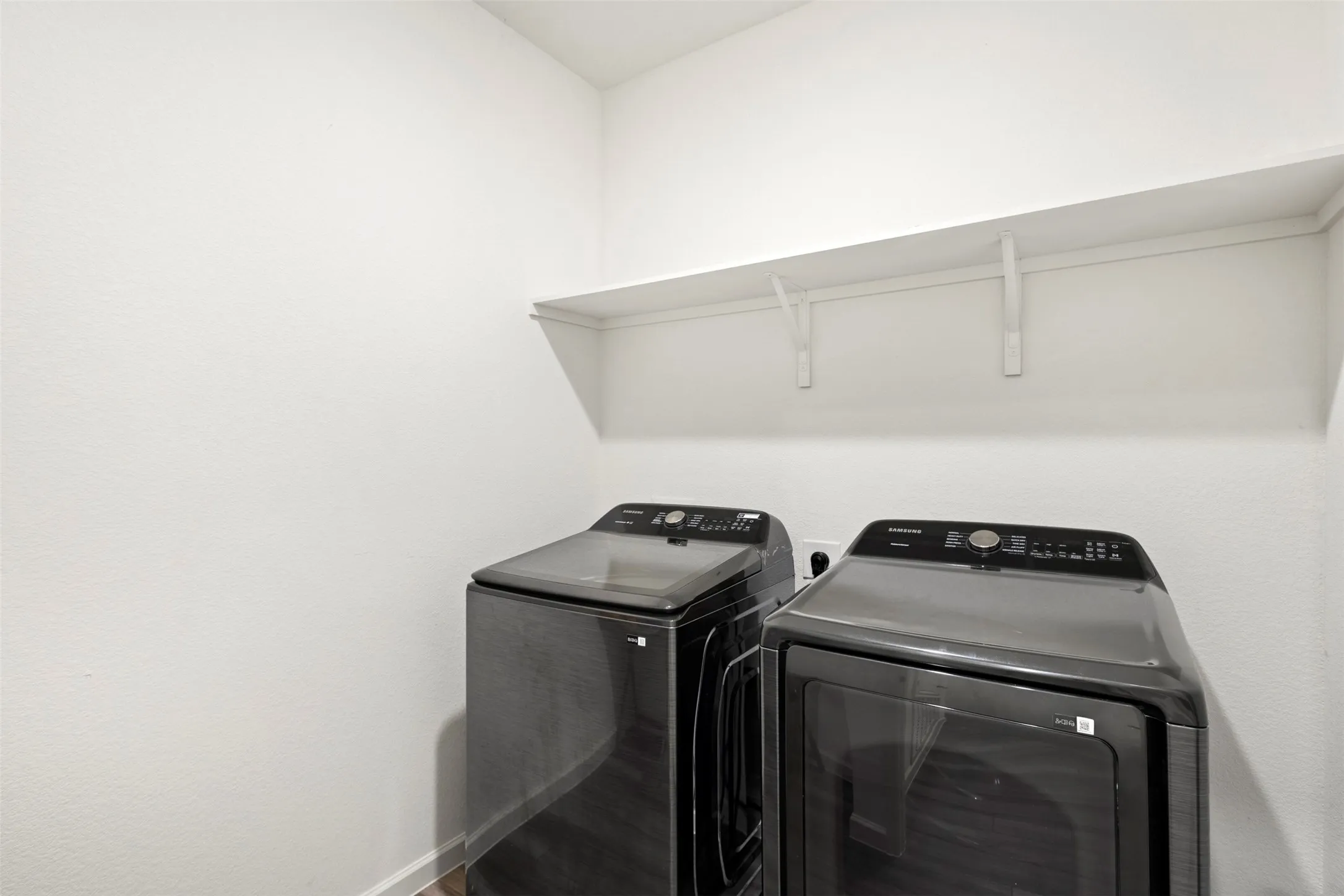 Laundry area featuring a built-in shelf and wood-finish flooring