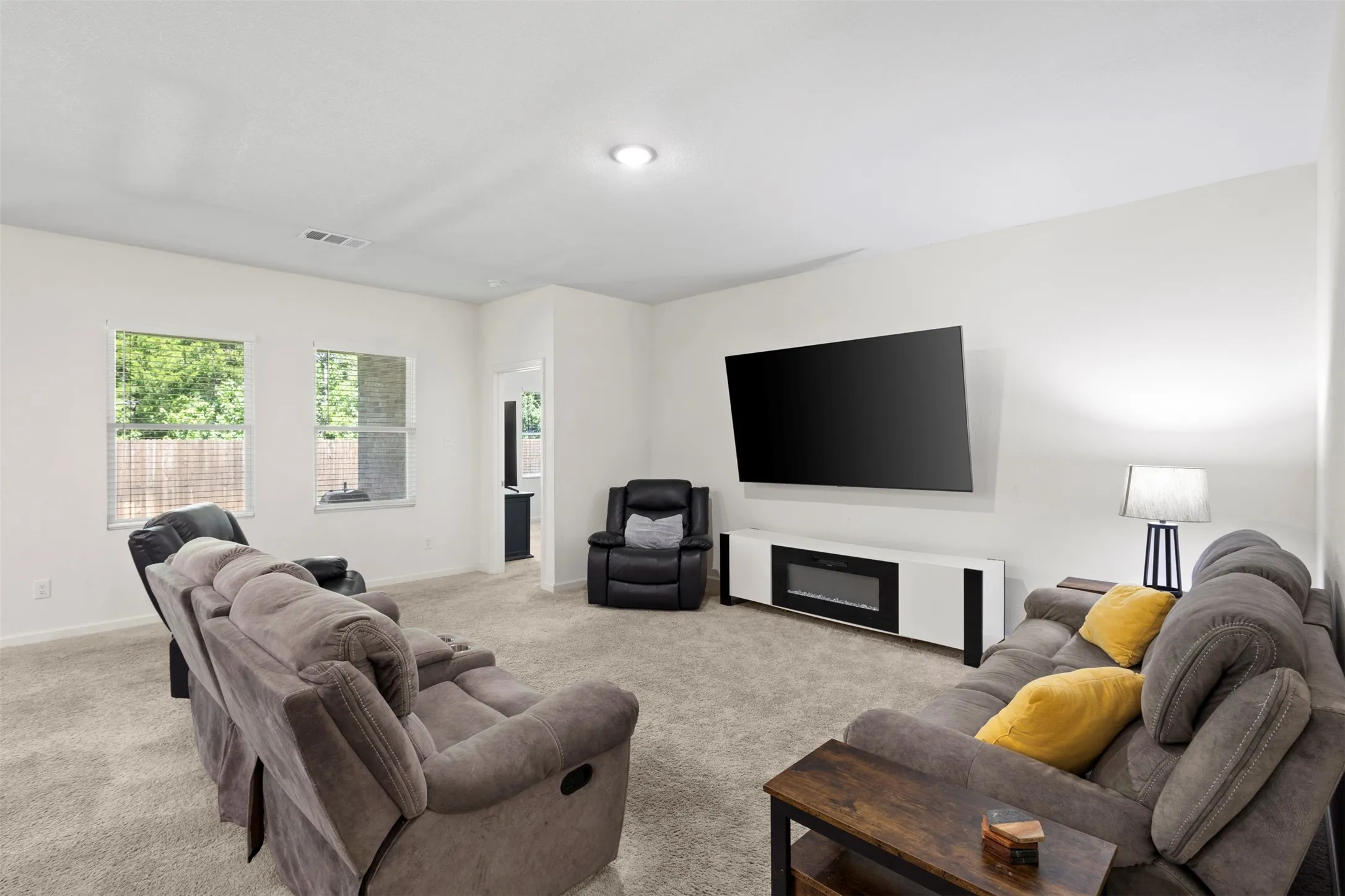 Spacious room featuring neutral wall tones, recessed lighting, carpet flooring, and multiple windows