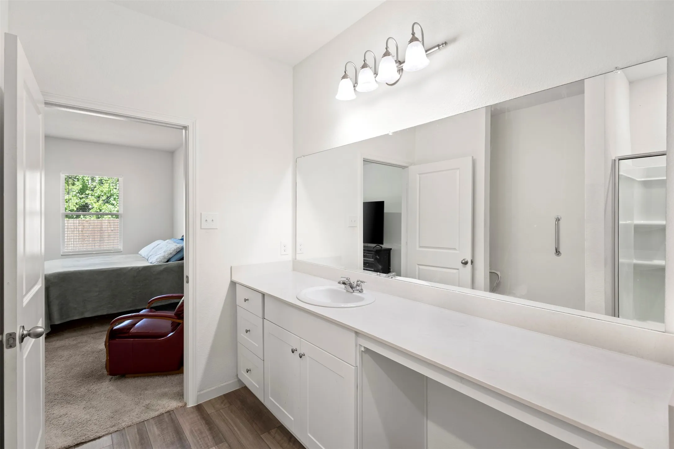 White vanity with chrome hardware, an integrated sink, and an expansive wall-mounted mirror