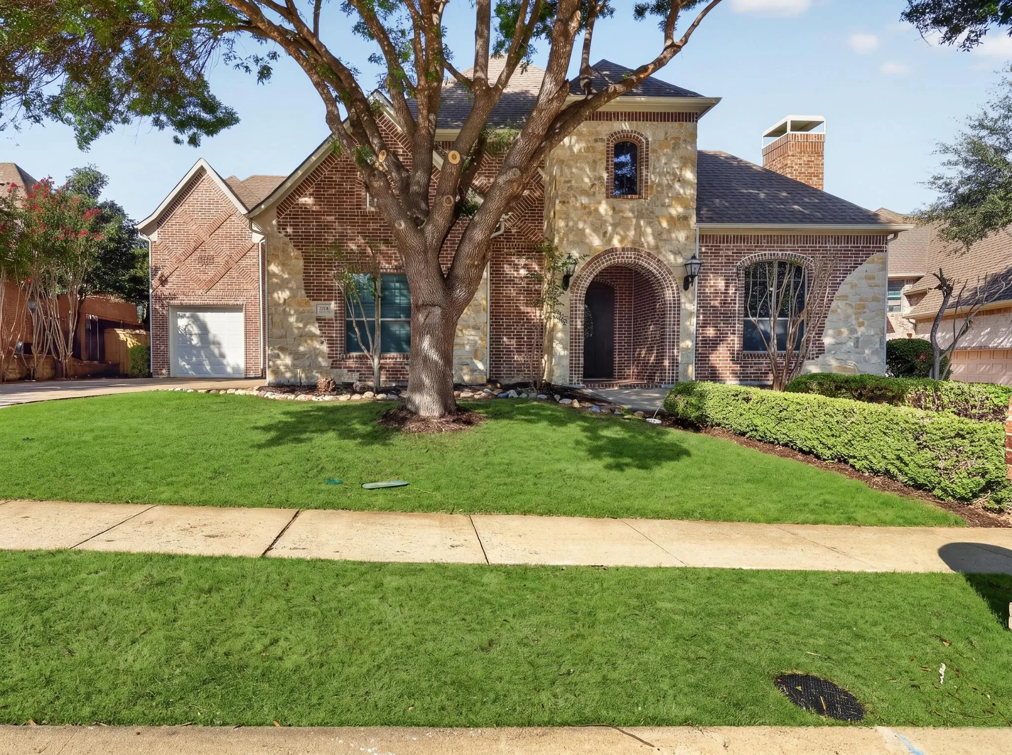 Brick and stone exterior with an arched entryway, and integrated 3 garage garage