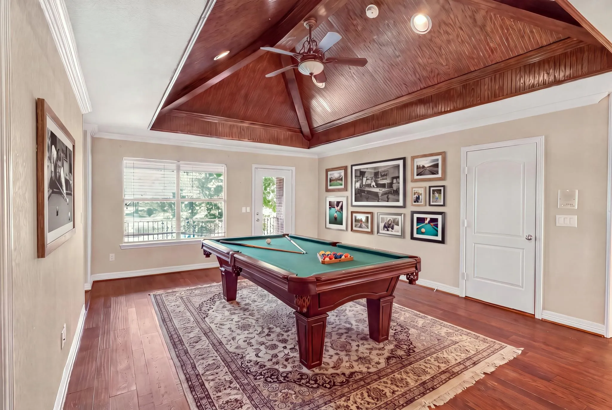 Virtually staged game room with vaulted wood-paneled ceiling wood-finish flooring, and recessed lighting. Balcony with water views.